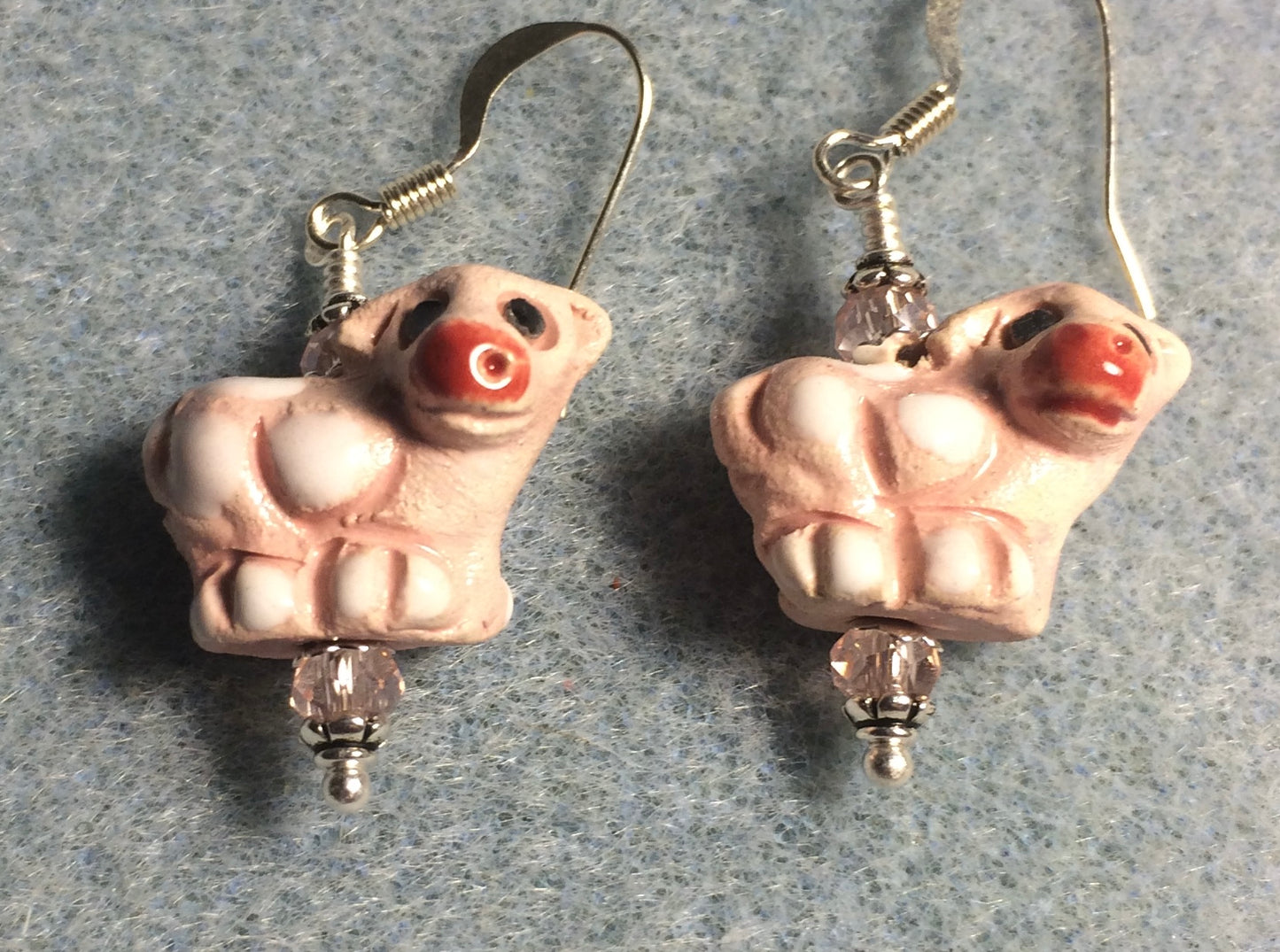 Small white and pink ceramic cow bead earrings adorned with small pink Chinese crystal beads.