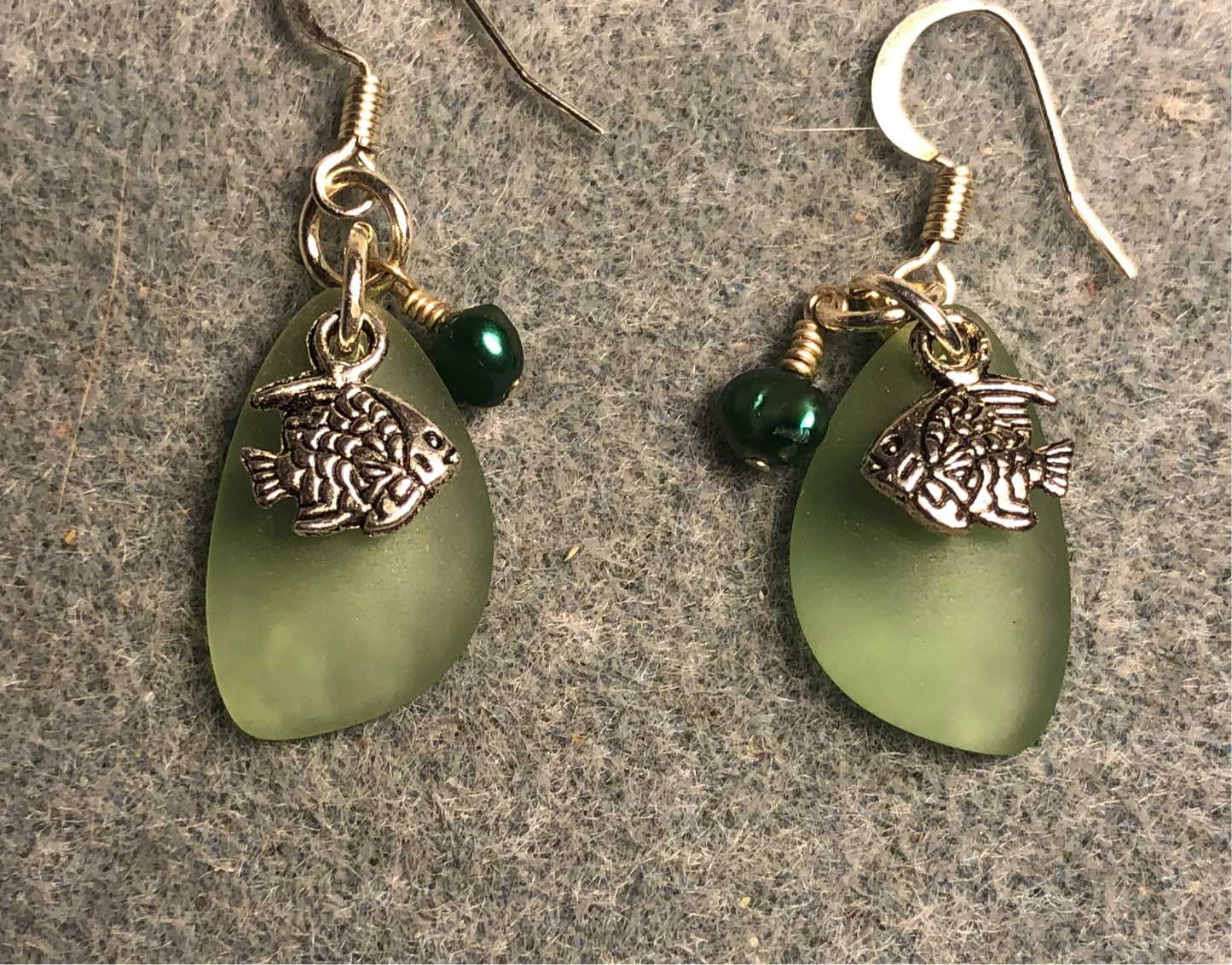 Small green sea glass pendant bead earrings adorned with small silver angelfish charms and small green pearl beads.