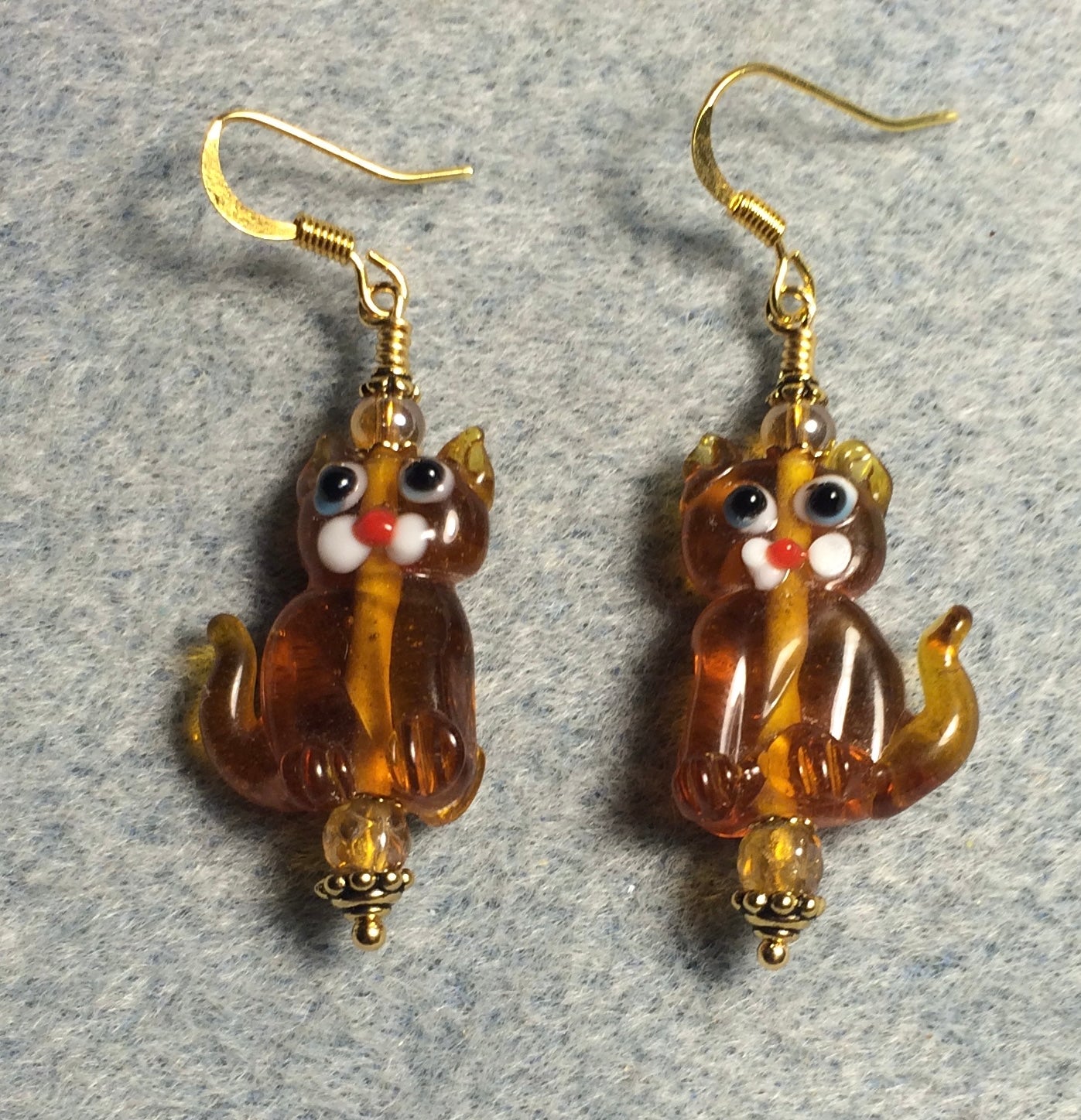 Translucent amber lamp work cat bead earrings adorned with amber Czech glass beads.