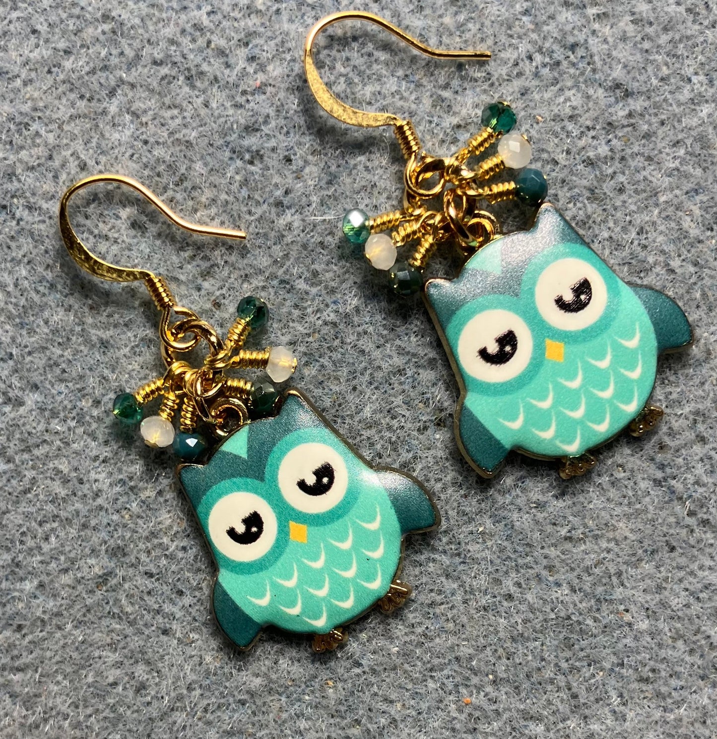 Teal and white enamel owl charm earrings adorned with tiny dangling teal and white Chinese crystal beads.