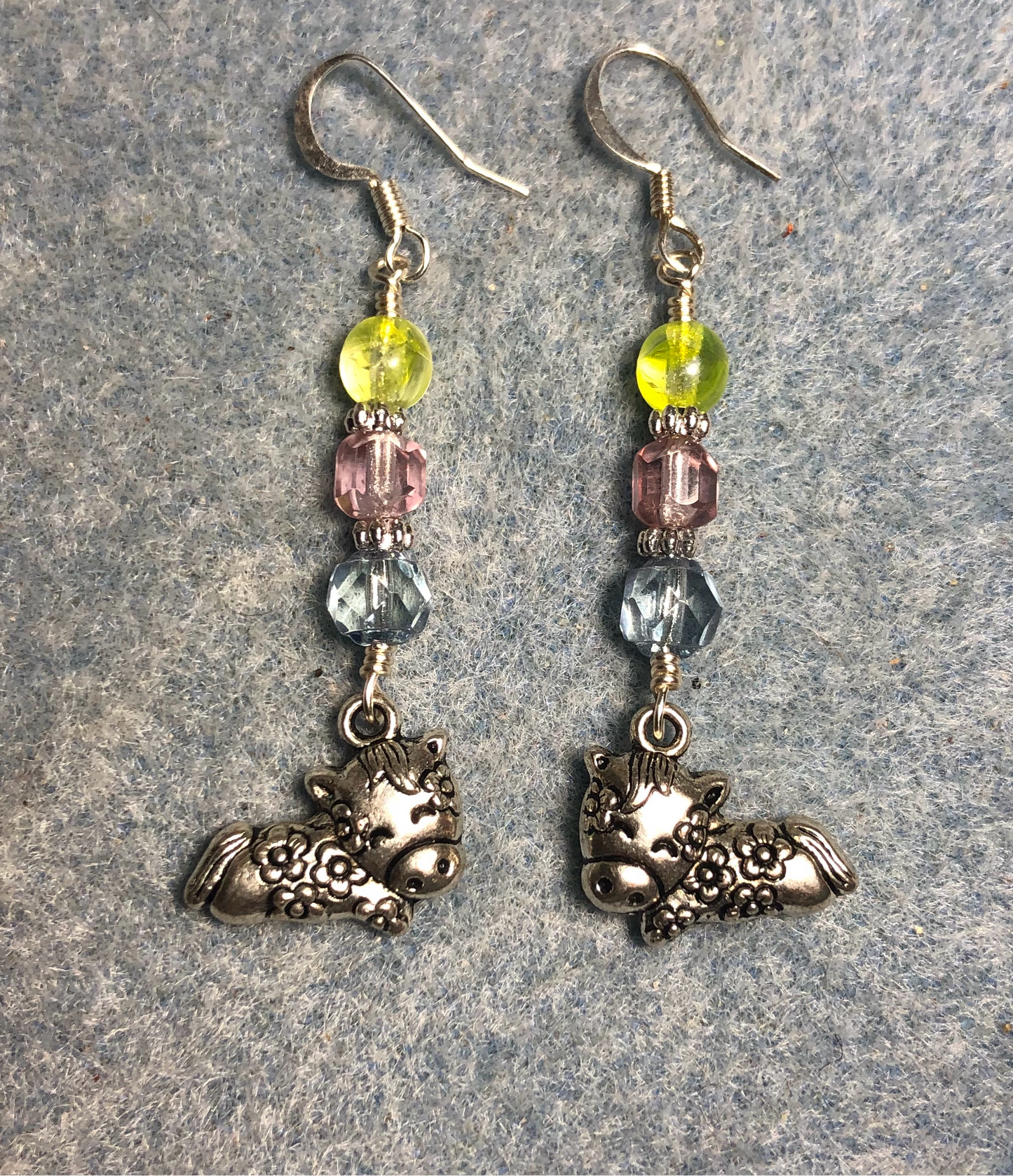 Silver sleeping cow charm earrings adorned with light blue, light pink, and lemon yellow Czech glass beads.