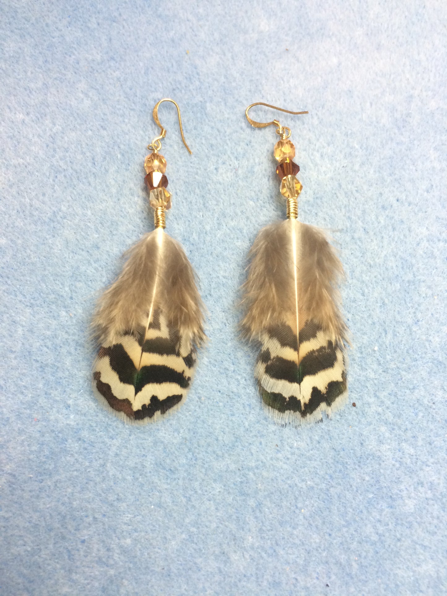 Brown striped peacock body feather earrings adorned with brown and amber Czech glass beads.
