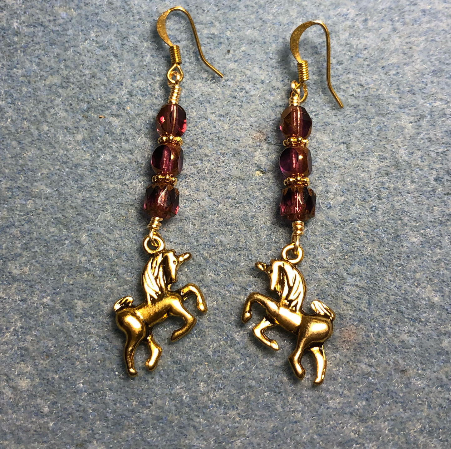 Gold unicorn charm earrings adorned with purple Czech glass beads
