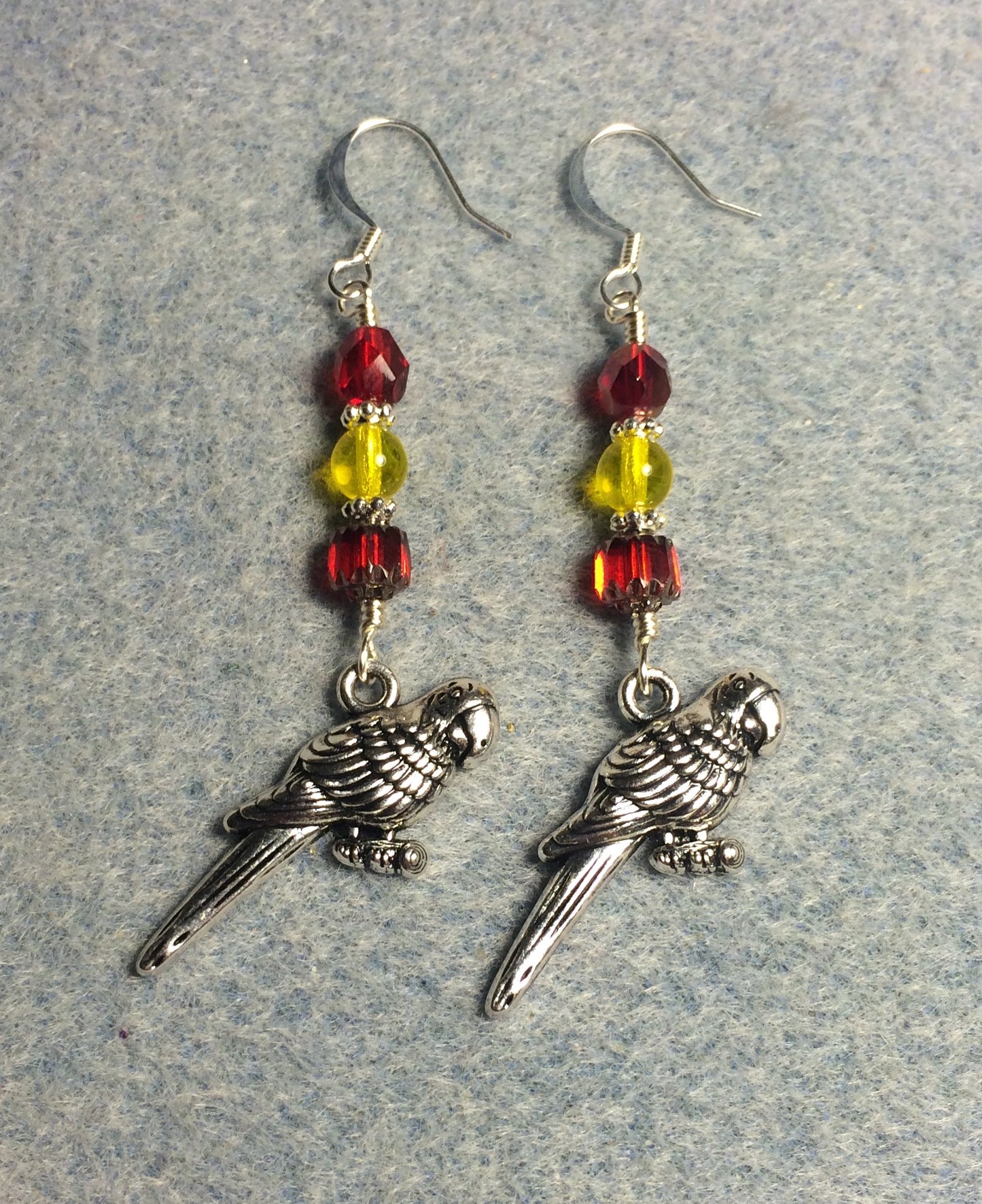 Large silver macaw charm earrings adorned with red and yellow Czech glass beads