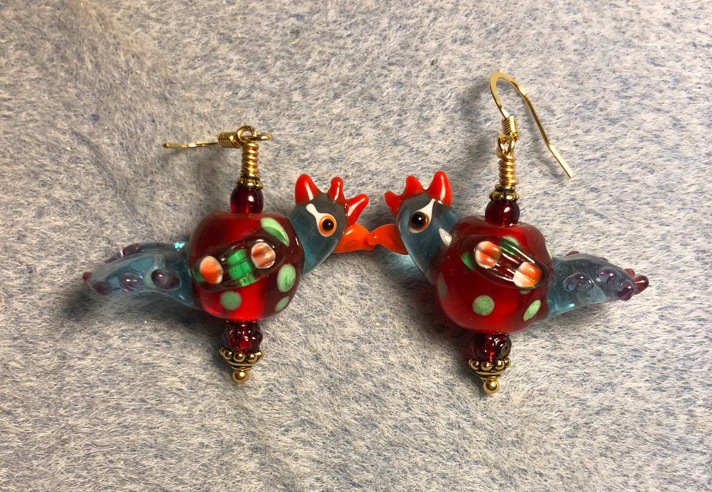 Translucent dark red and blue polka dotted lamp work chicken bead earrings adorned with dark red Czech glass beads.