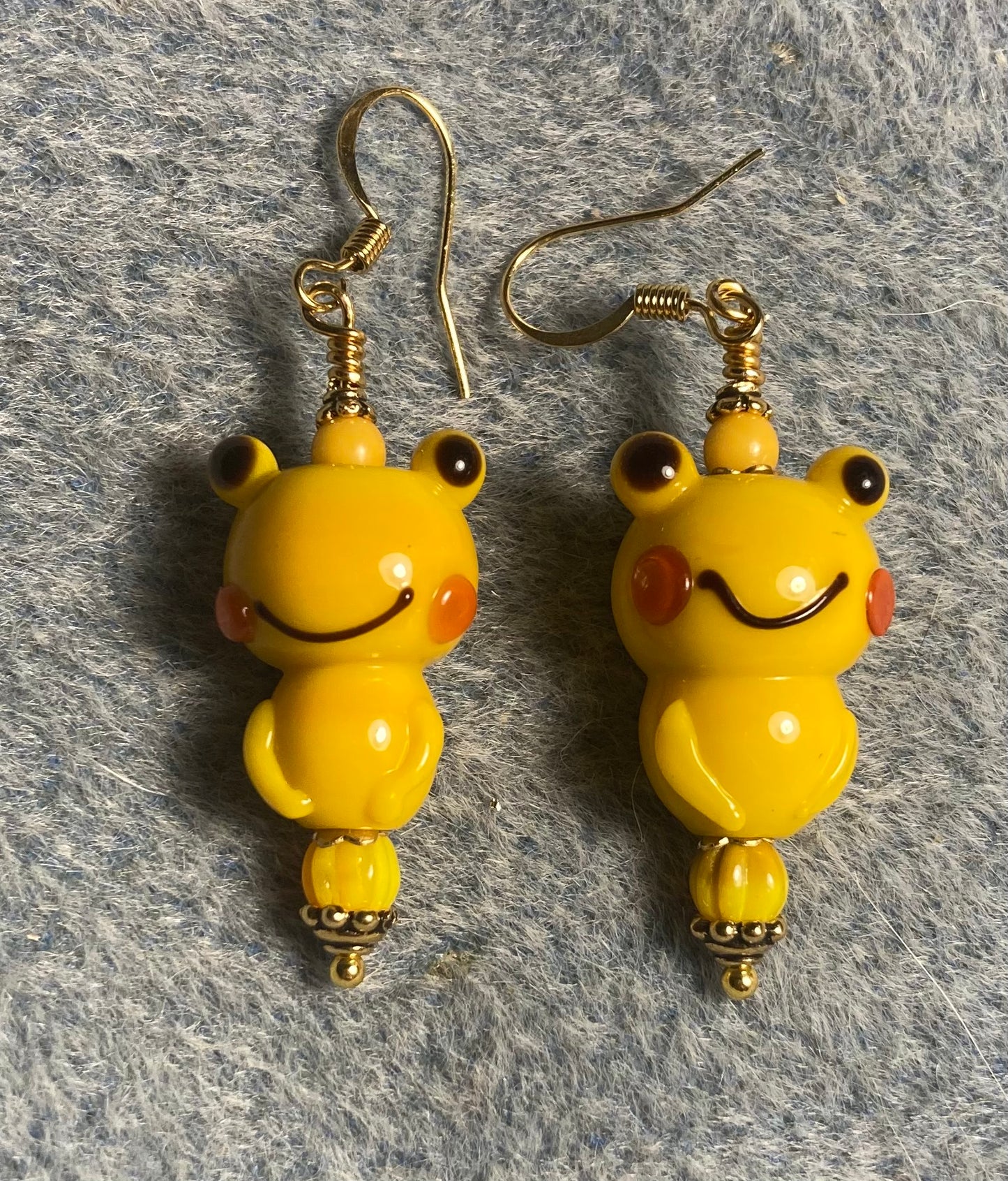 Golden yellow lamp work frog bead earrings adorned with golden yellow Czech glass beads.