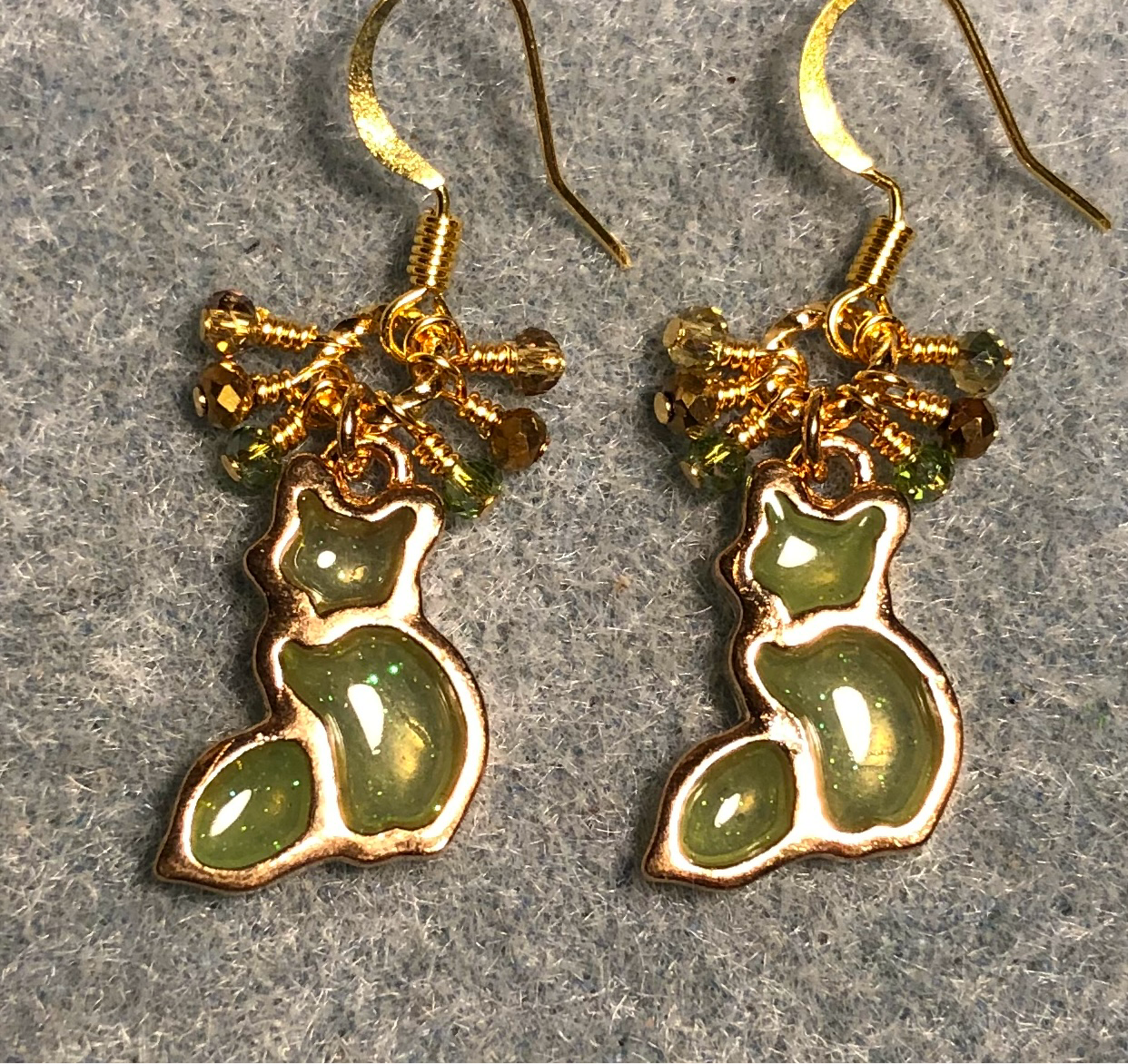 Olive green and gold sparkly resin cat charm earrings adorned with small dangling olive green and gold Chinese crystal beads.