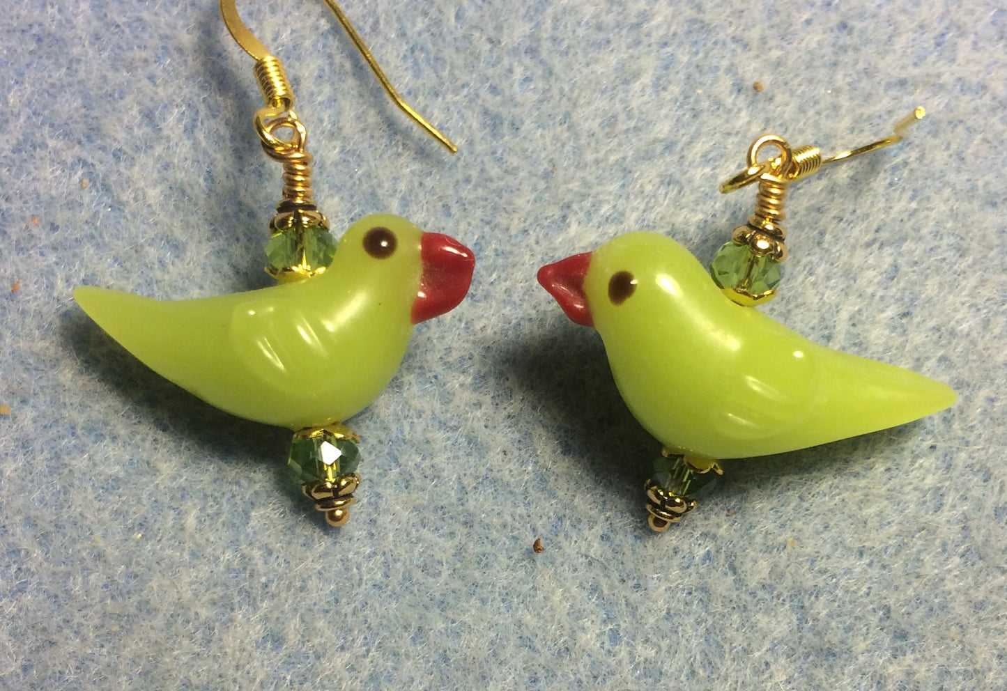 Opaque olive green lamp work songbird bead earrings adorned with olive green Chinese crystal beads.