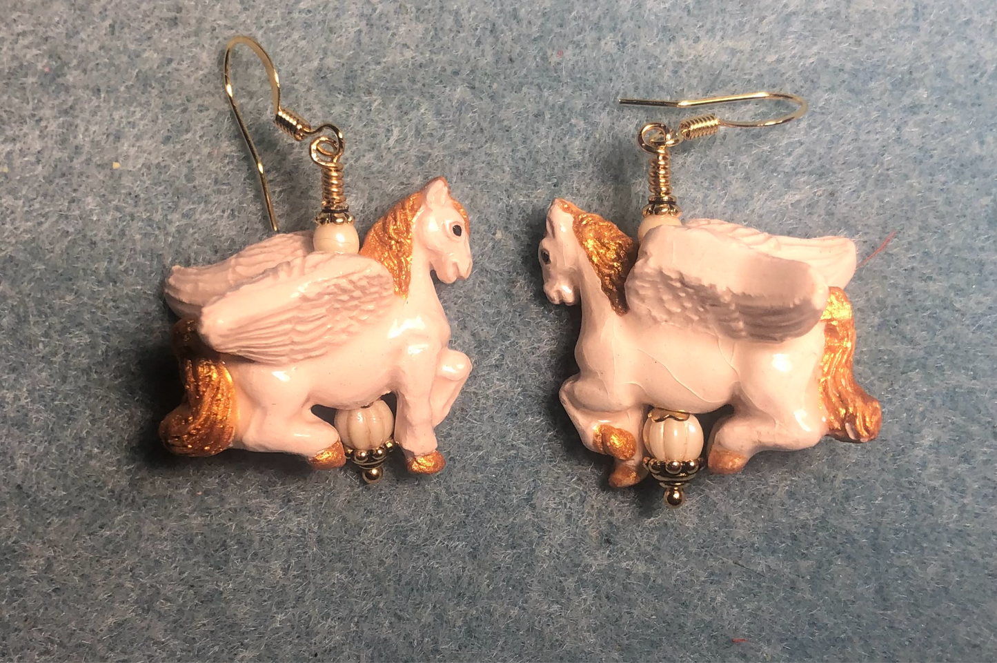 Large off white and gold Pegasus (flying horse) bead earrings adorned with off white Czech glass beads.