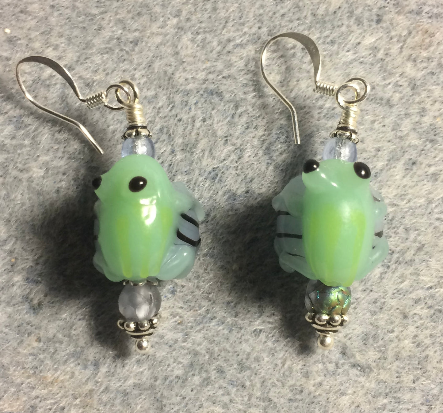 Green and light blue lamp work frog bead earrings adorned with light blue Czech glass beads.