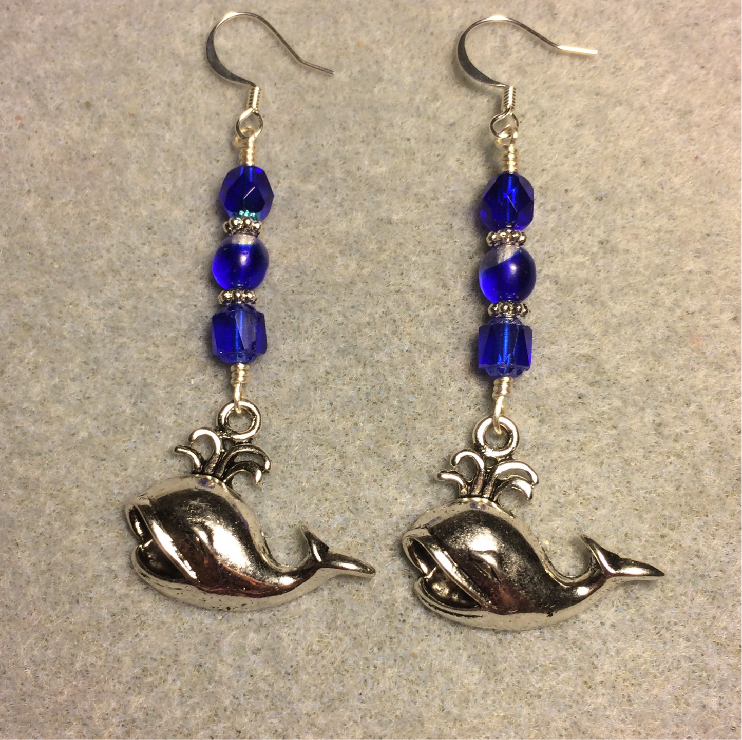 Silver spouting whale charm earrings adorned with dark blue Czech glass beads