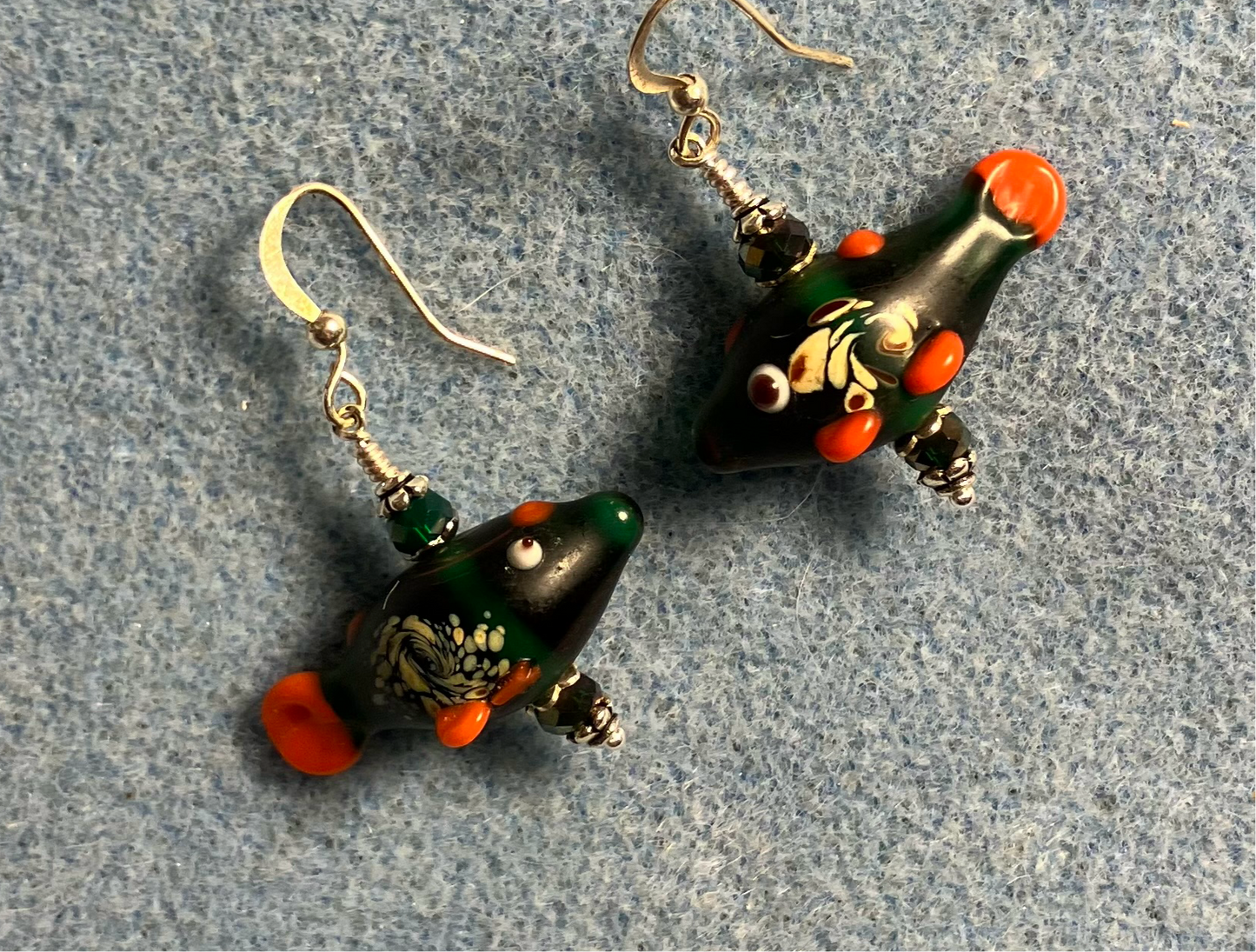 Emerald green lamp work fish bead earrings adorned with emerald green Chinese crystal beads.