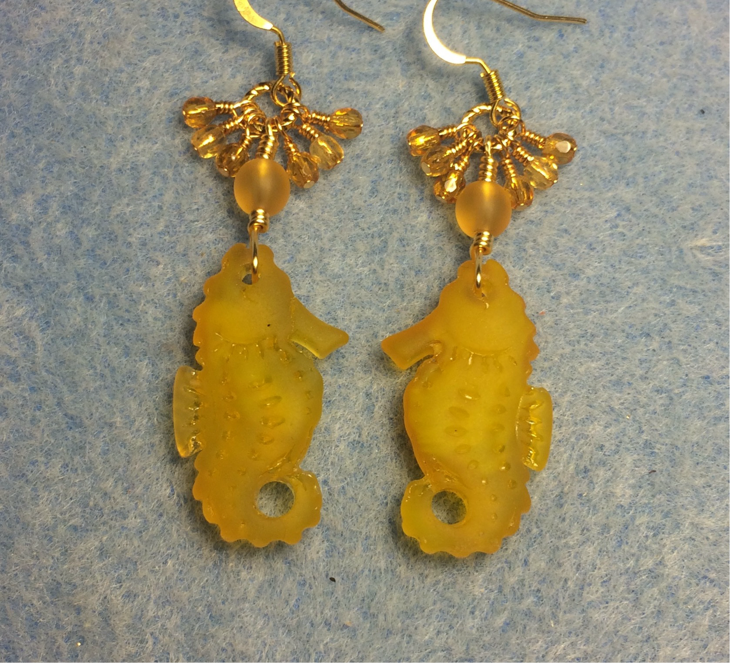 Amber sea glass seahorse pendant bead earrings adorned with amber Czech glass beads and small dangling amber Czech glass beads.