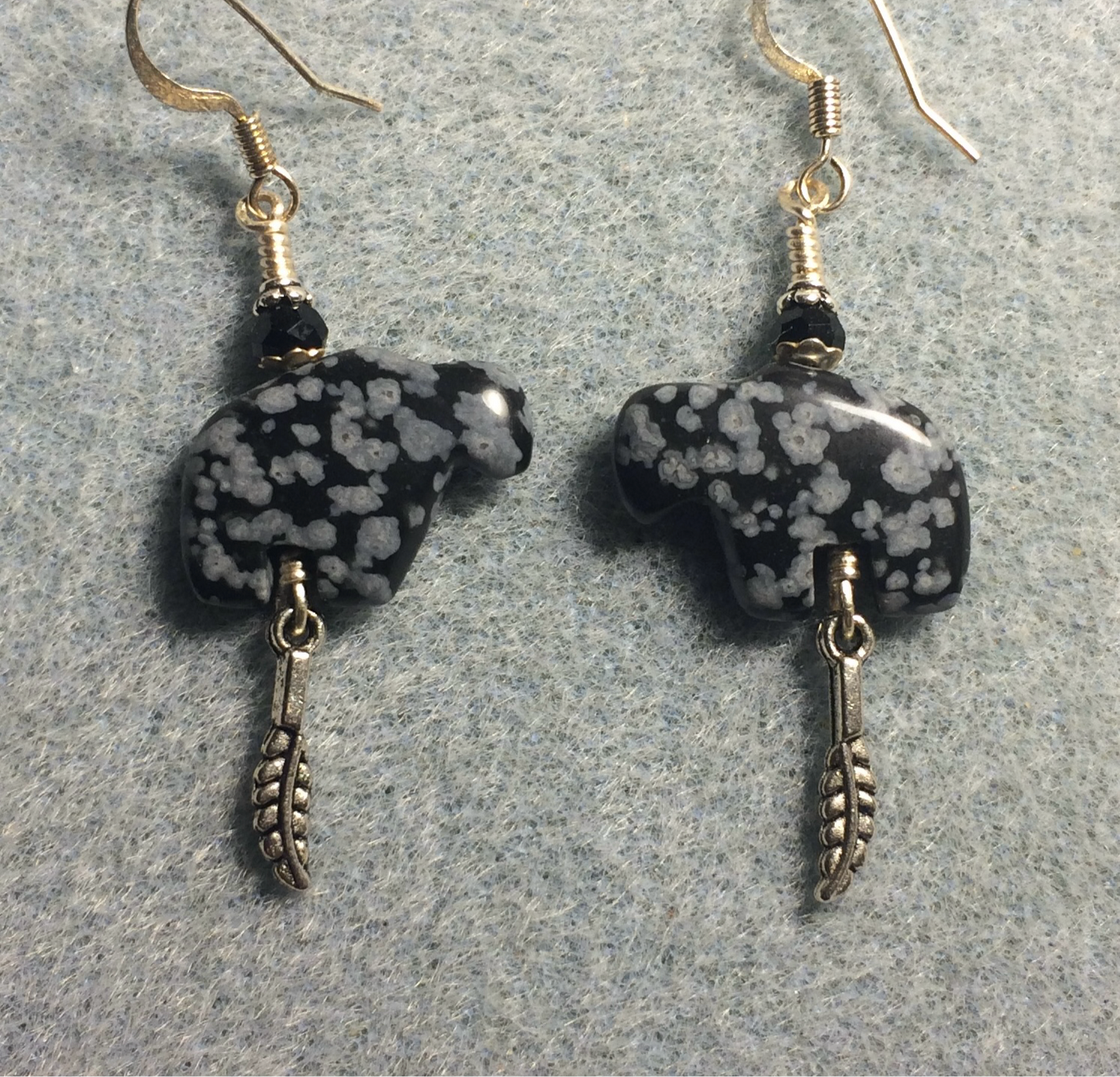 Snowflake obsidian gemstone buffalo fetish bead earrings adorned with black crystal beads and tiny silver feather charms.