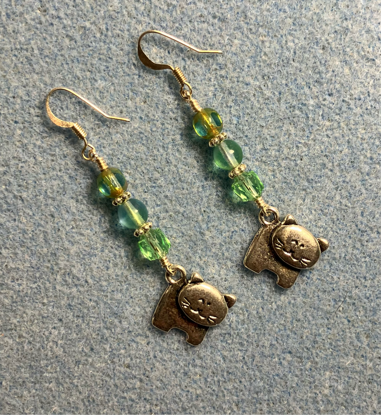 Silver cat charm earrings adorned with light green Czech glass beads