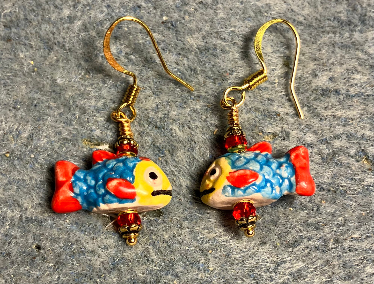 Small turquoise, red, and yellow ceramic fish bead earrings adorned with red Chinese crystal beads.