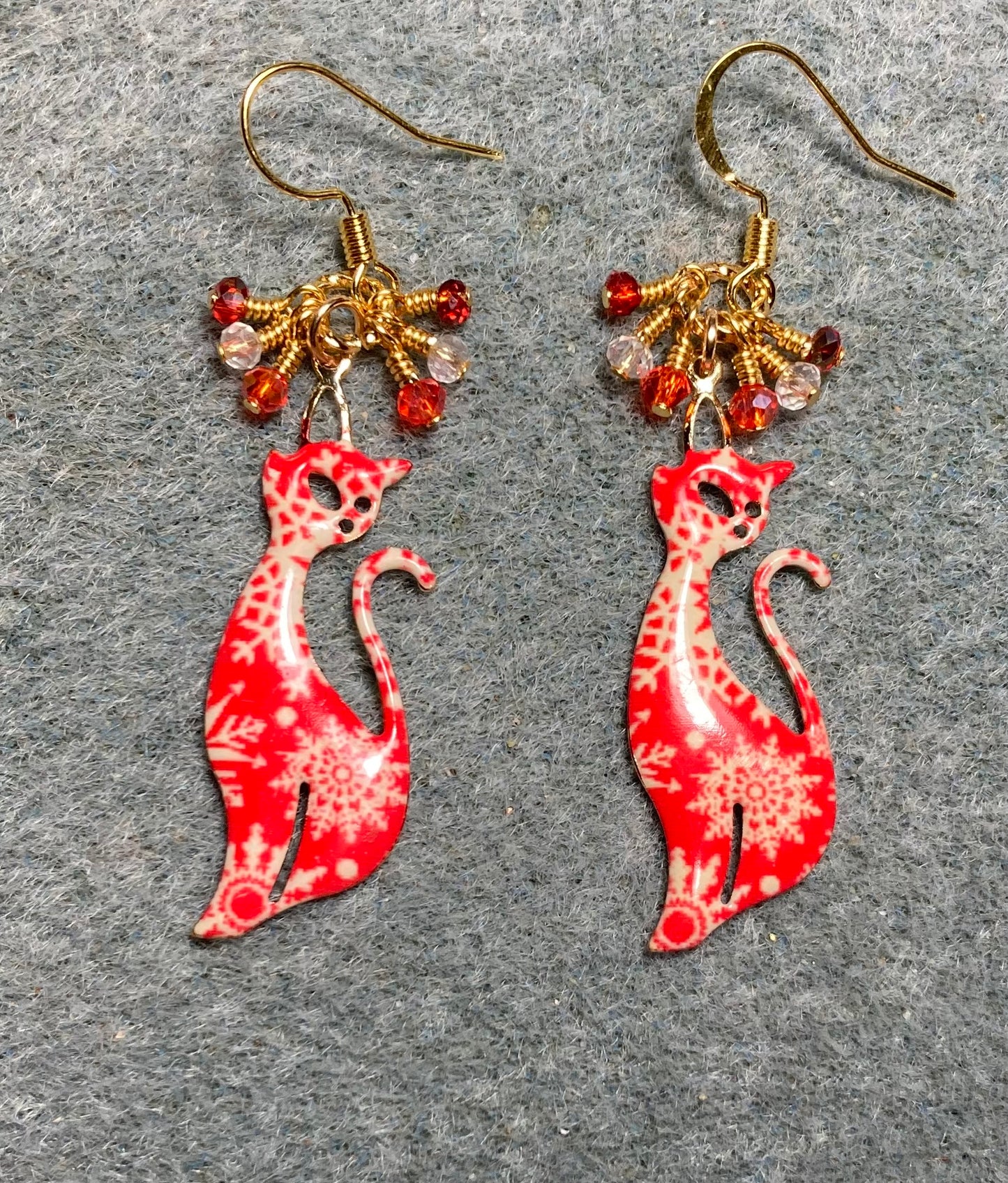 Red and white enamel snowflake patterned cat charm earrings adorned with tiny dangling red and clear Chinese crystal beads.