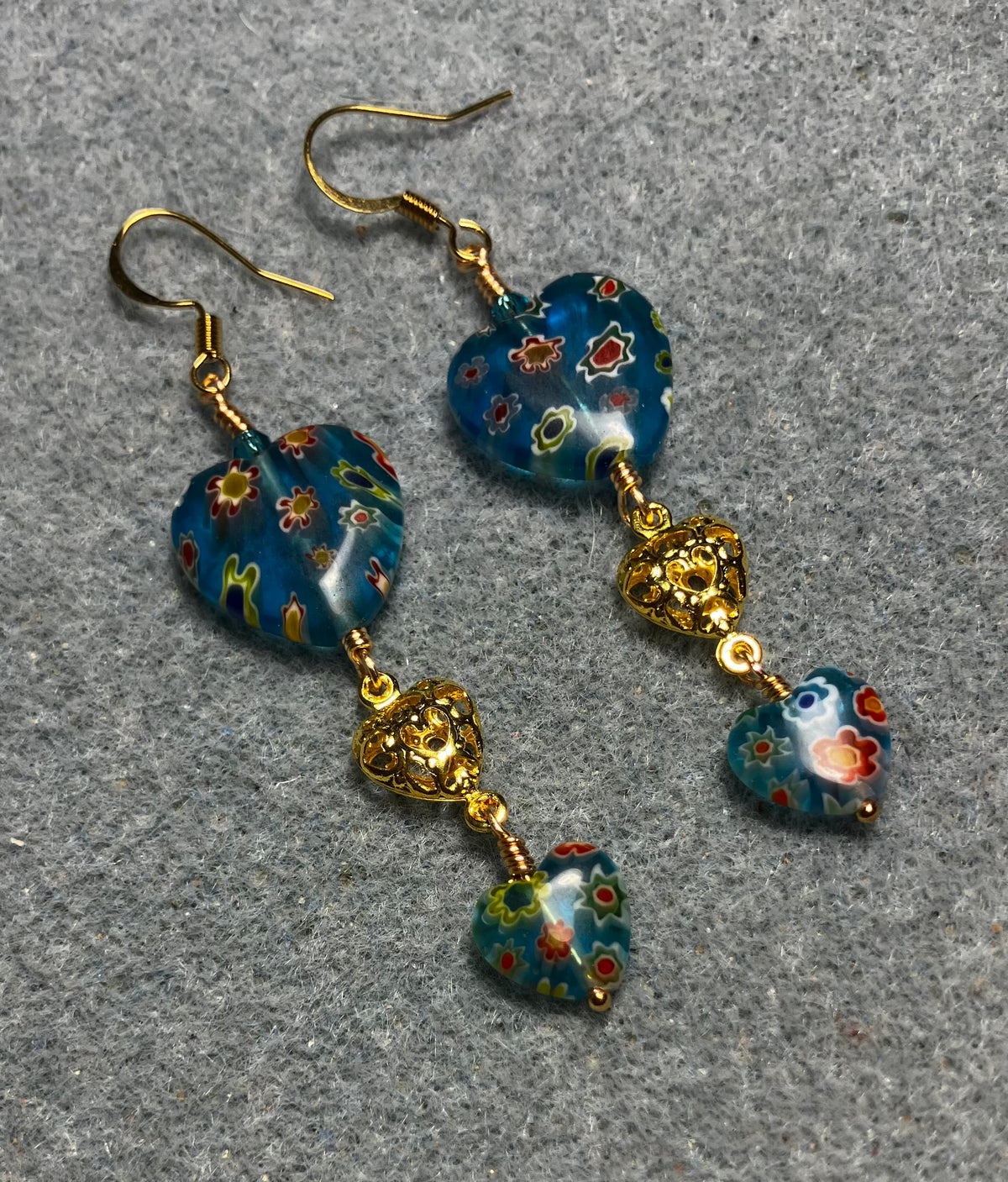 Large and small matching turquoise millefiori glass heart bead earrings joined by gold filigree heart connectors.