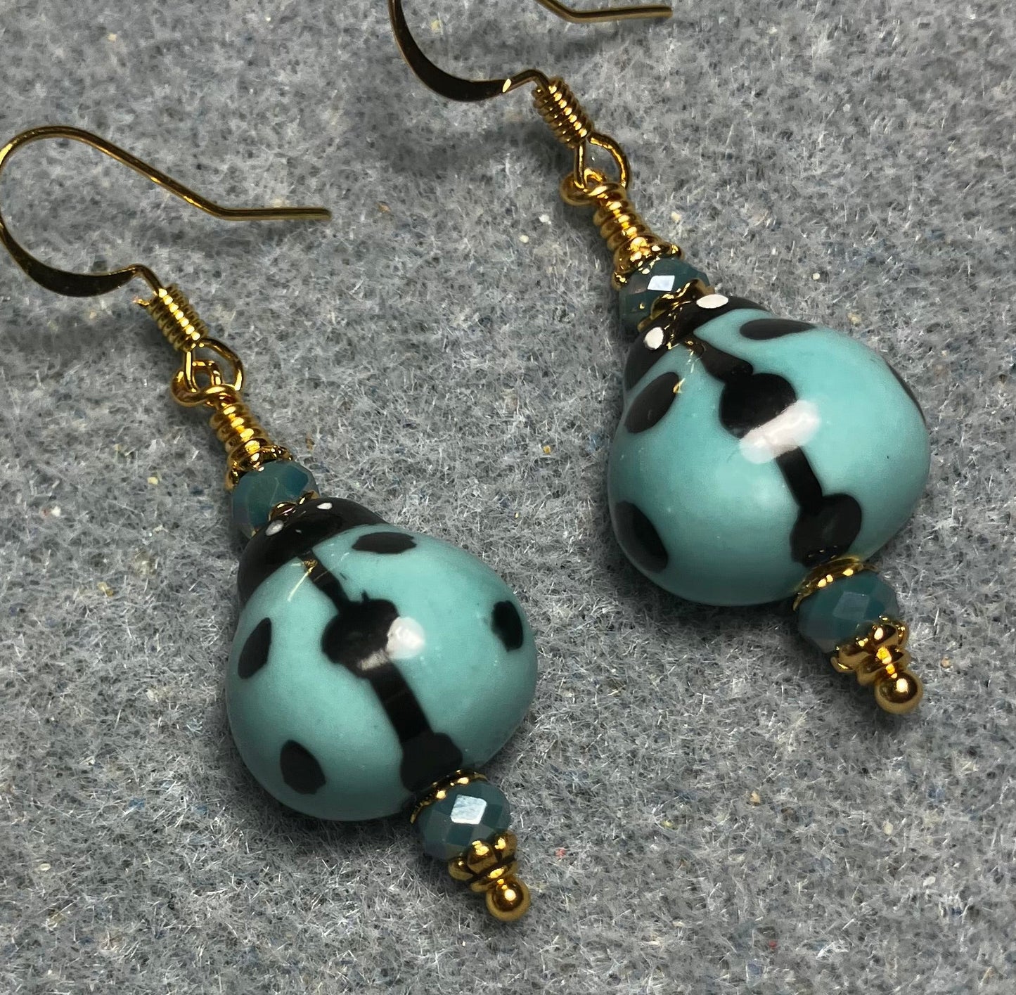 Light teal and black ceramic ladybug bead earrings adorned with teal Chinese crystal beads.
