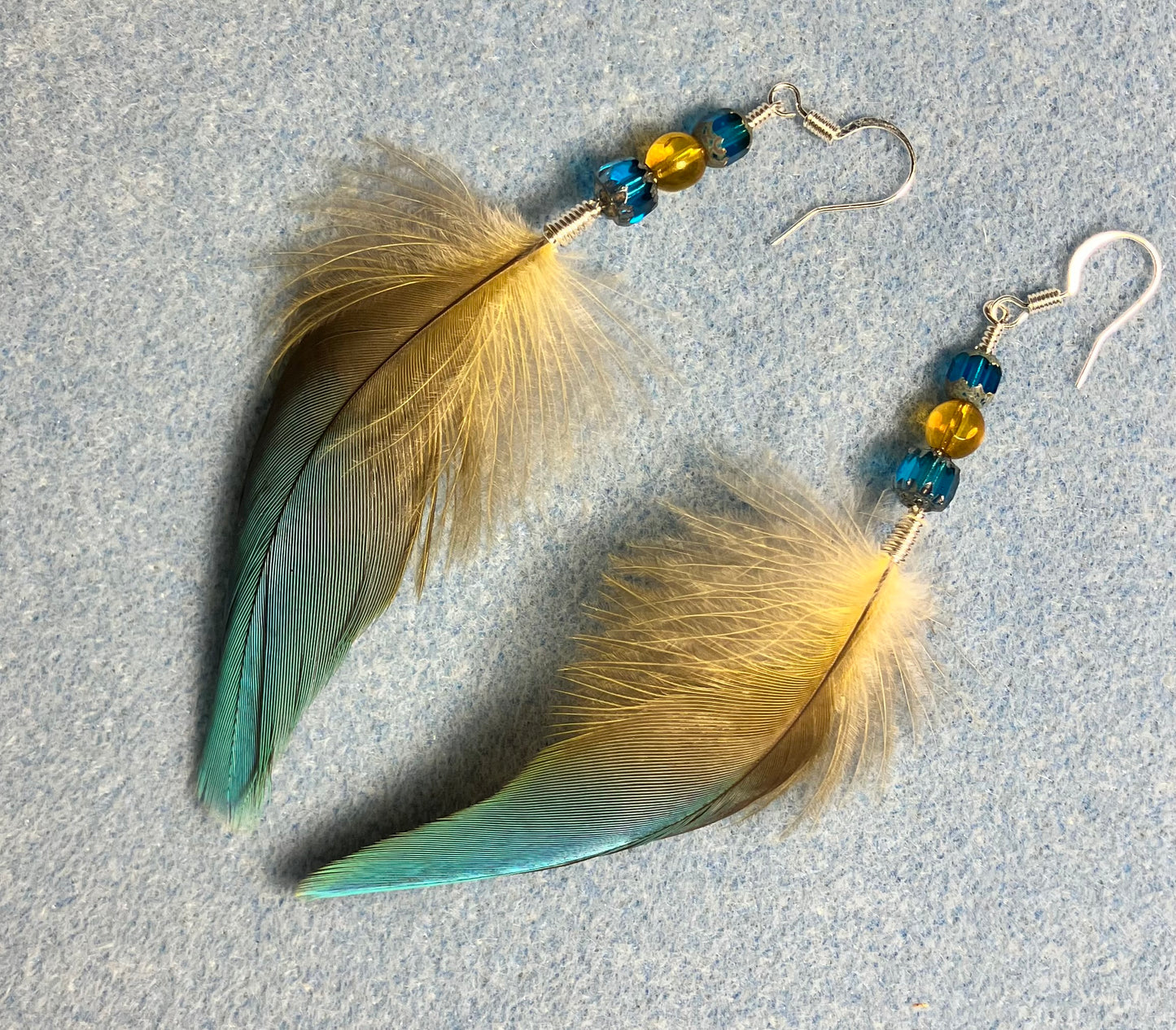 Blue macaw feather earrings adorned with blue and yellow Czech glass beads.