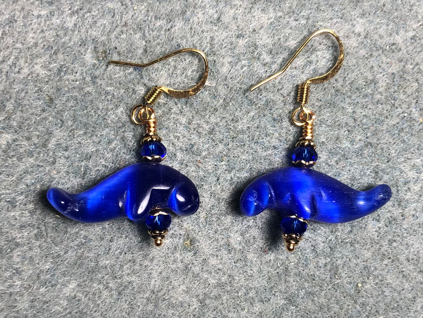 Dark blue fiber optic (cat’s eye) manatee bead earrings adorned with dark blue Chinese crystal beads.