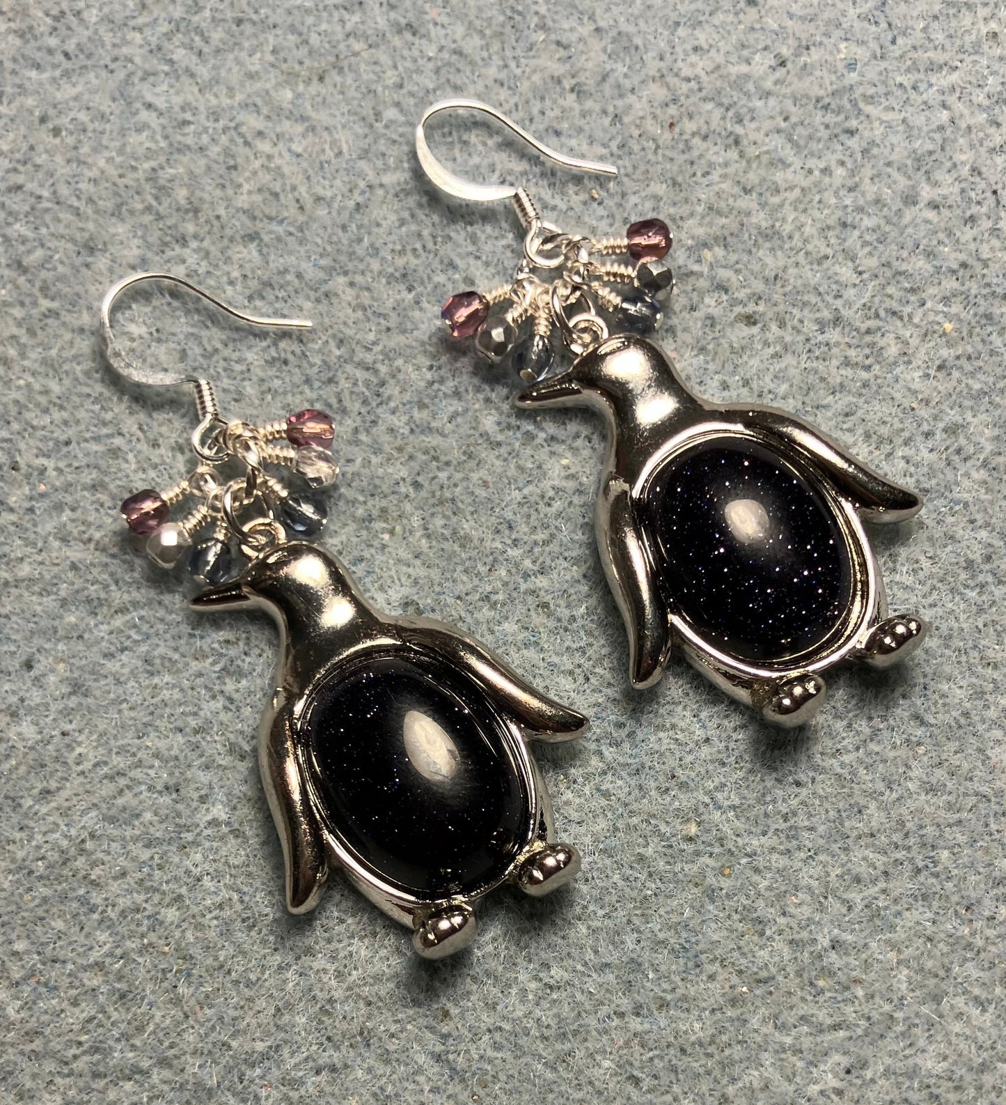 Large silver and blue goldstone gemstone penguin charm earrings adorned with small dangling blue, purple, and silver Czech glass beads.