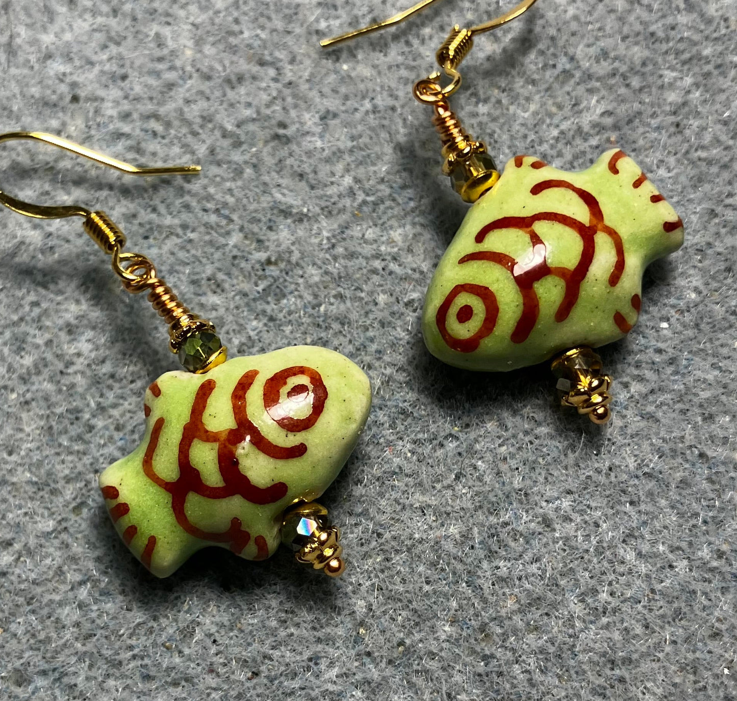 Olive green and dark red ceramic fish bead earrings adorned with sparkly olive green Chinese crystal beads.