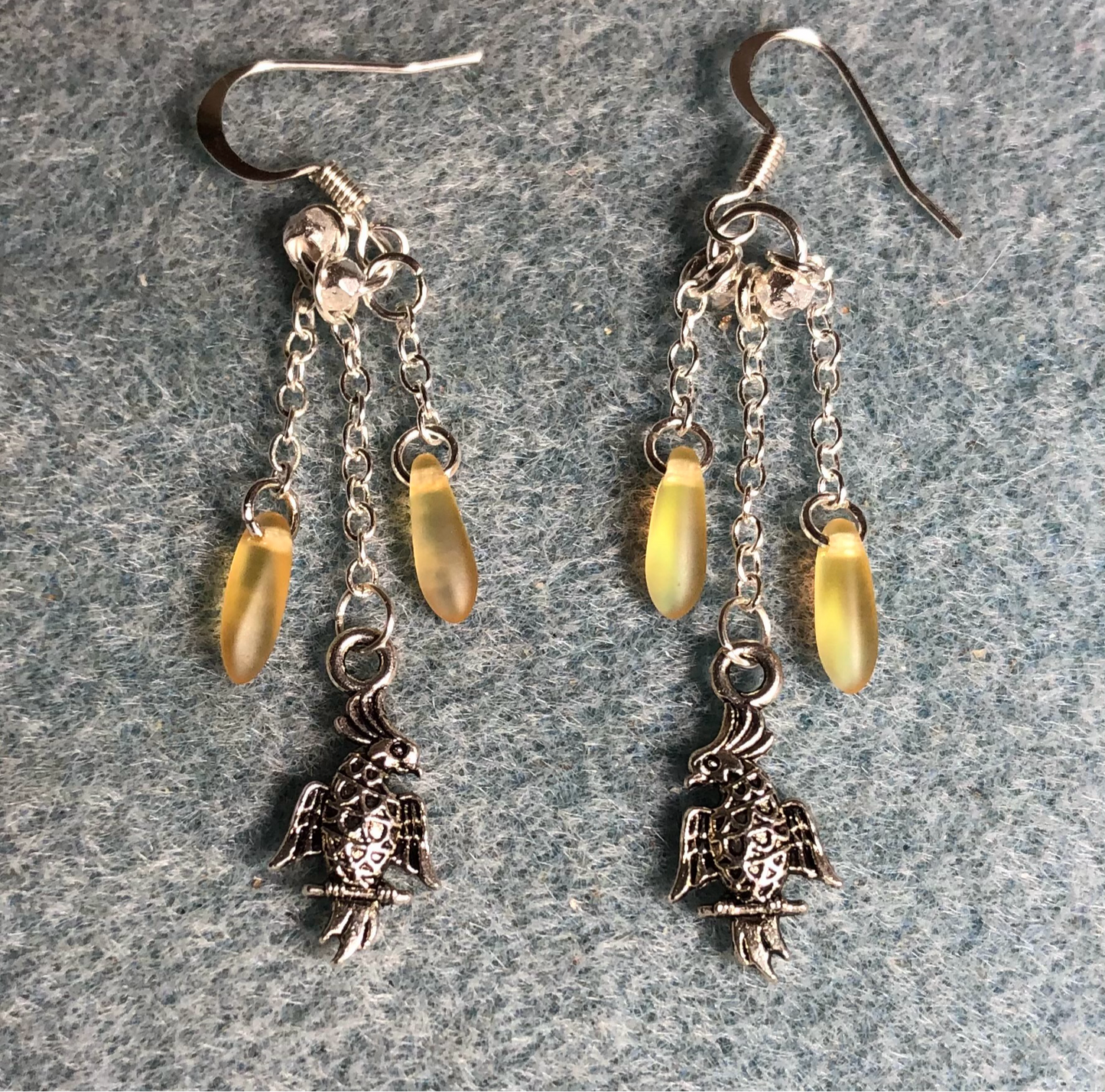 Small silver cockatoo charm earrings attached to silver chain and adorned with small yellow Czech glass dagger beads