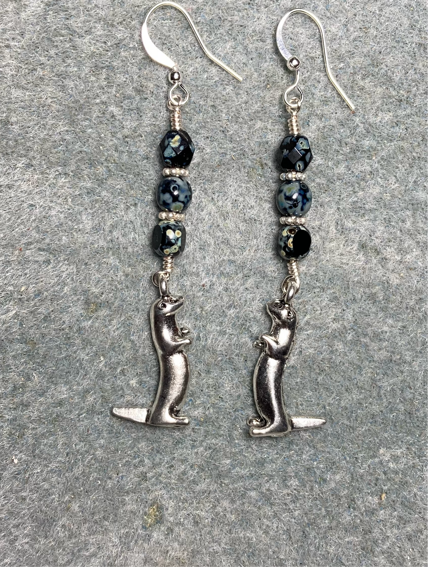 Silver standing otter charm earrings adorned with black Picasso Czech glass beads
