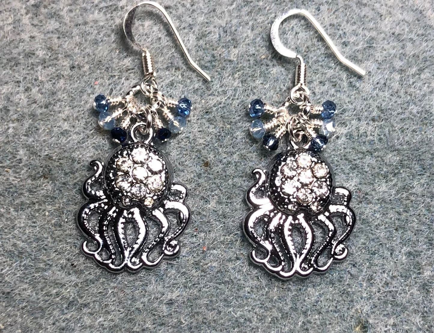 Silver and clear rhinestone octopus charm earrings adorned with tiny dangling light blue, silver, and dark blue Chinese crystal beads.