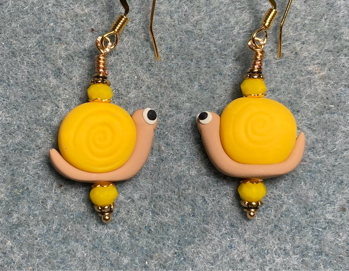 Golden yellow and tan polymer clay snail bead earrings adorned with golden yellow Chinese crystal beads.