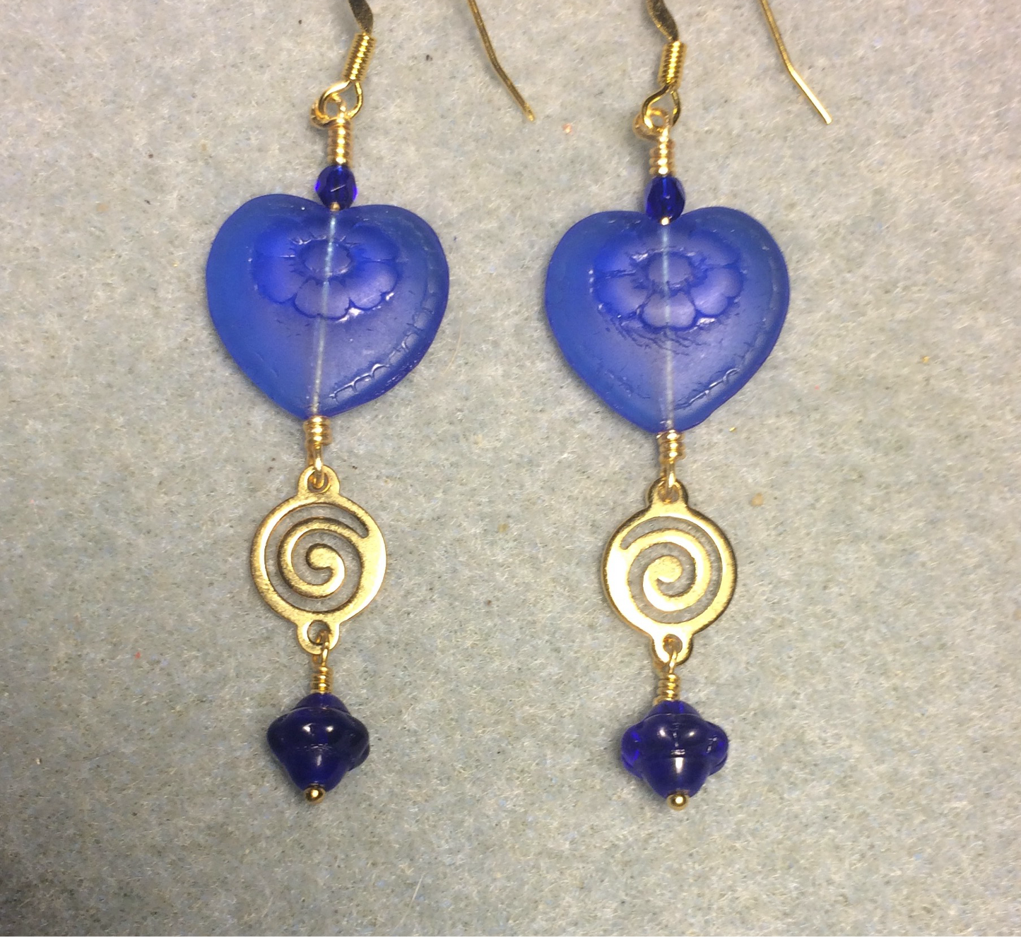 Dark blue Czech glass heart bead earrings adorned with gold swirly links and dark blue Czech glass Saturn beads.