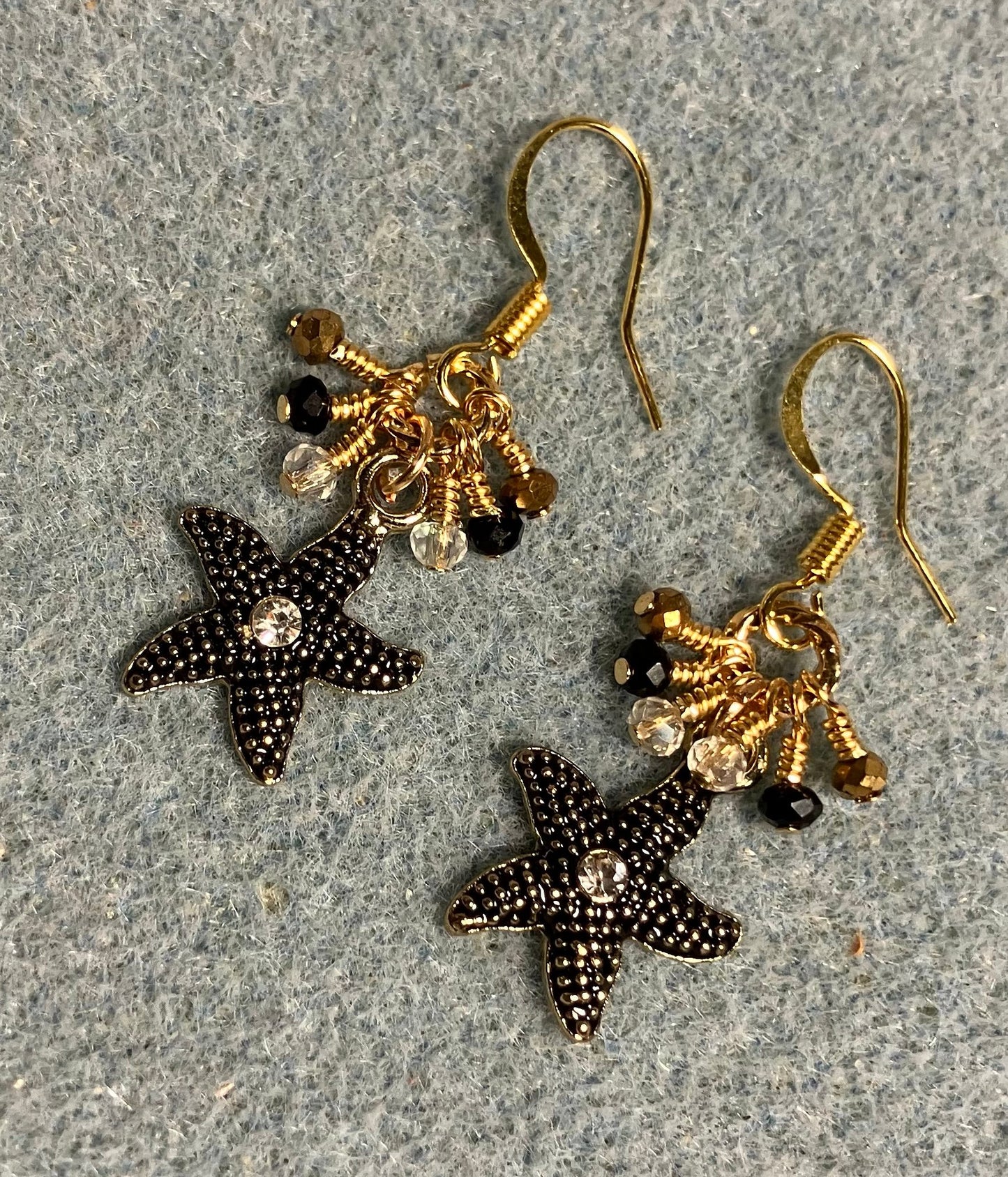 Black and gold enamel starfish charm earrings adorned with tiny dangling black, gold, and clear Chinese crystal beads.