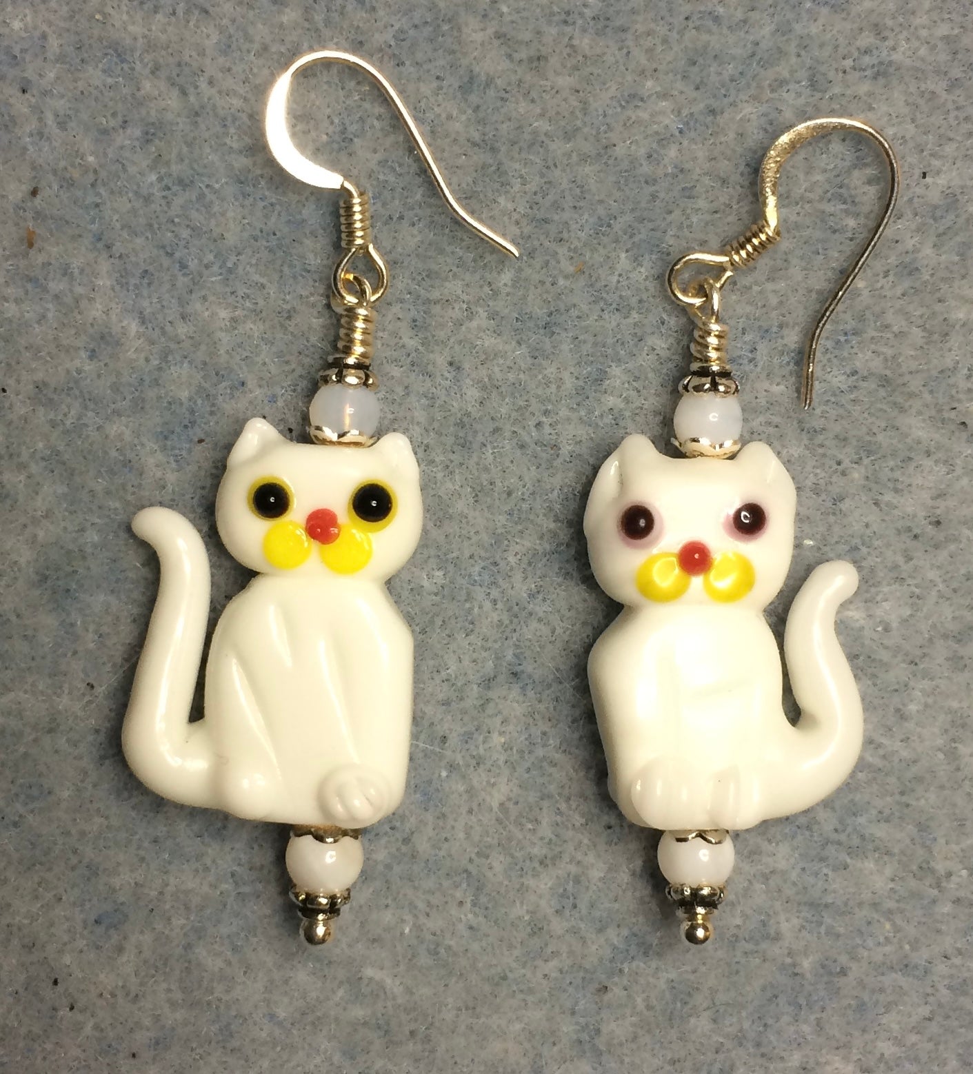 Opaque white lamp work cat bead earrings adorned with white Czech glass beads.