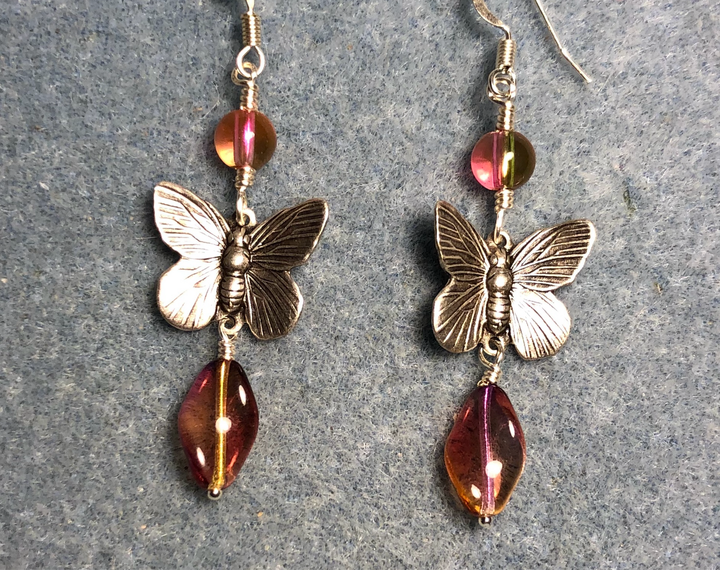 Silver butterfly connector charm earrings adorned with pinkish yellow Czech glass twist beads and pinkish yellow Czech glass beads.
