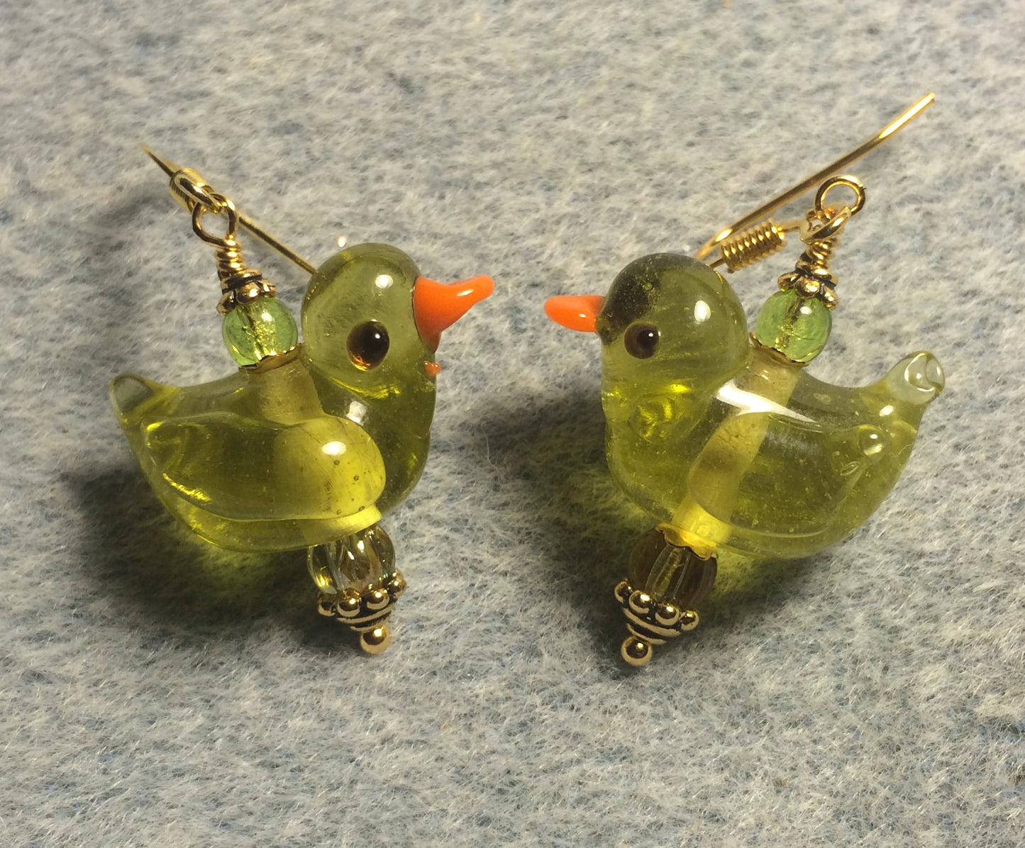 Translucent olive green lamp work duck bead earrings adorned with olive green Czech glass beads.