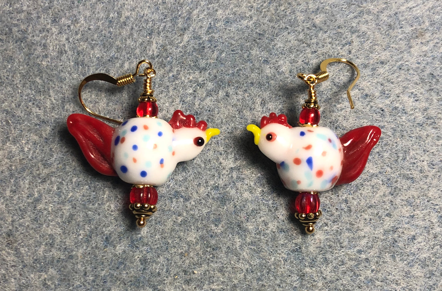 Red and white polka dotted lamp work rooster bead earrings adorned with red Czech glass beads.