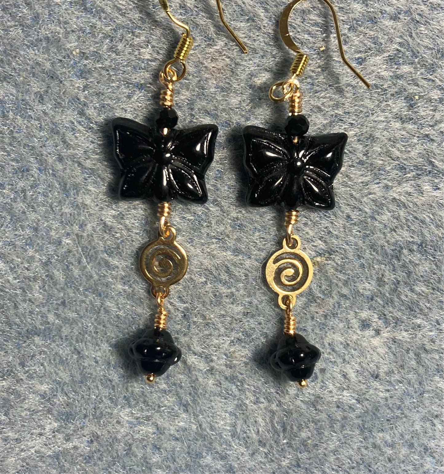 Black Czech glass butterfly bead earrings adorned with gold swirly connectors and black Czech glass daisy beads.