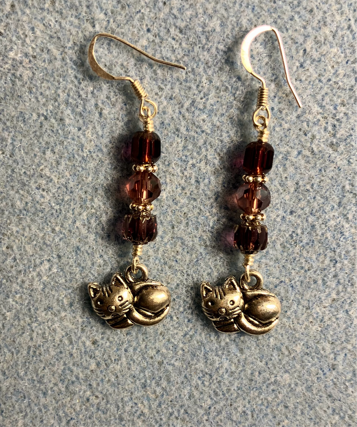 Silver sleeping cat charm earrings adorned with purple Czech glass beads.