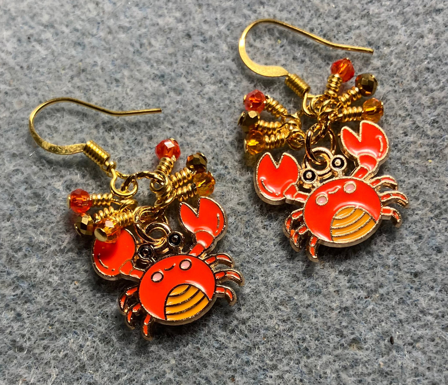 Small orange and gold enamel crab charm earrings adorned with tiny dangling orange and gold Chinese crystal beads.