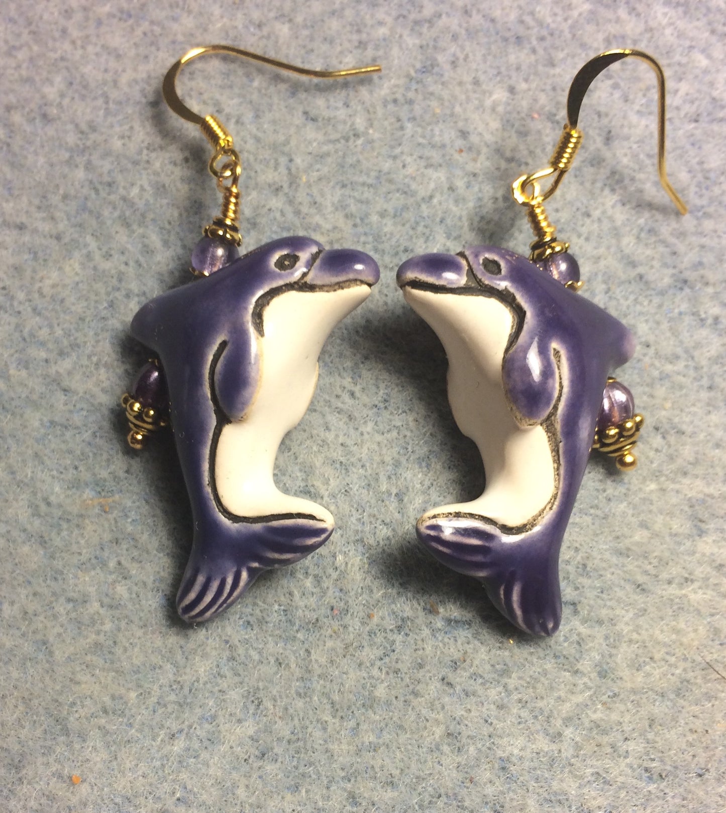 Purple and white ceramic dolphin bead earrings adorned with purple Czech glass beads.