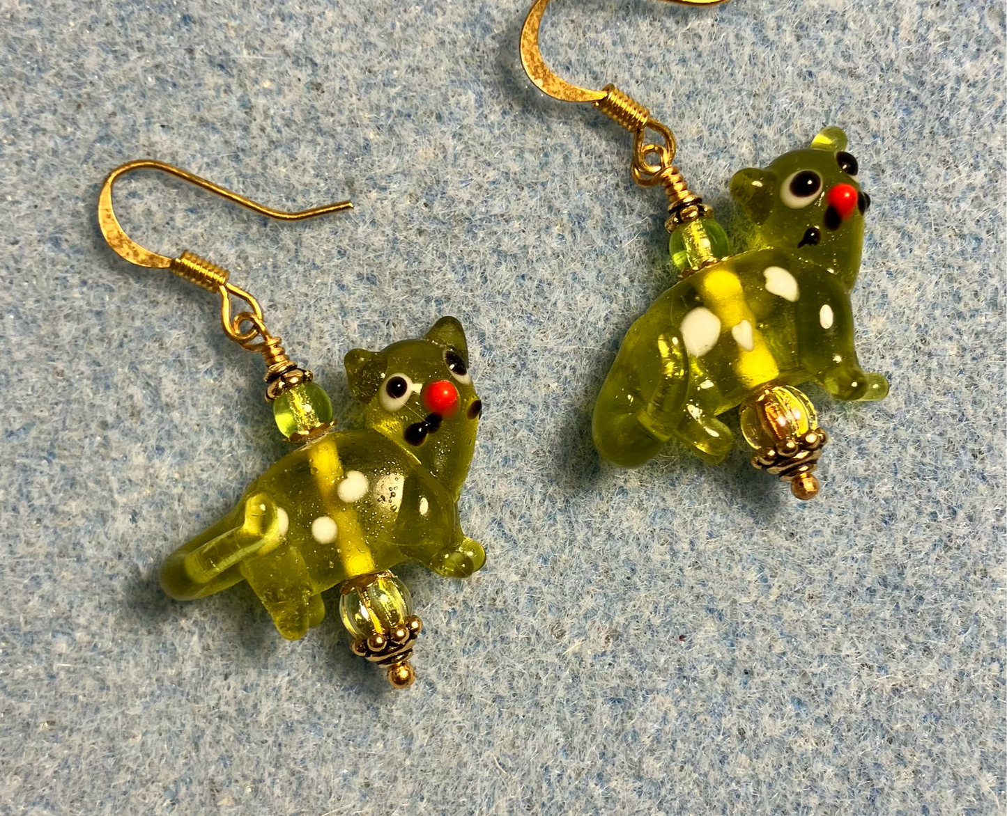 Translucent olive green lamp work spotted cat bead earrings adorned with olive green Czech glass beads.