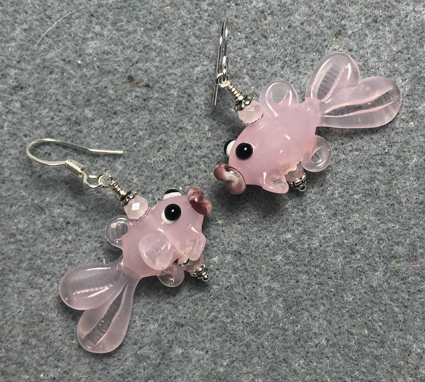 Opaque light pink lamp work fish bead earrings adorned with light pink Chinese crystal beads.