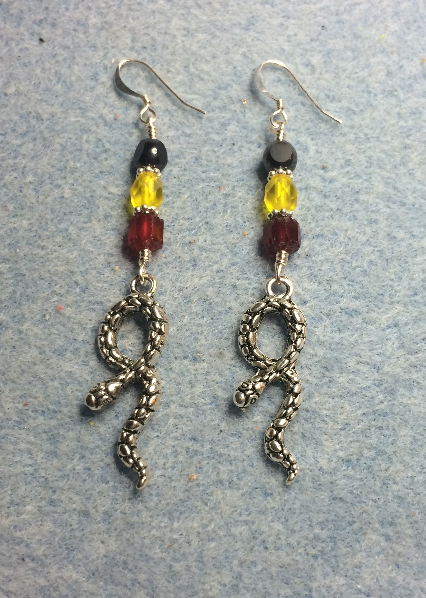 Silver snake charm earrings adorned with red, yellow, and black Czech glass beads