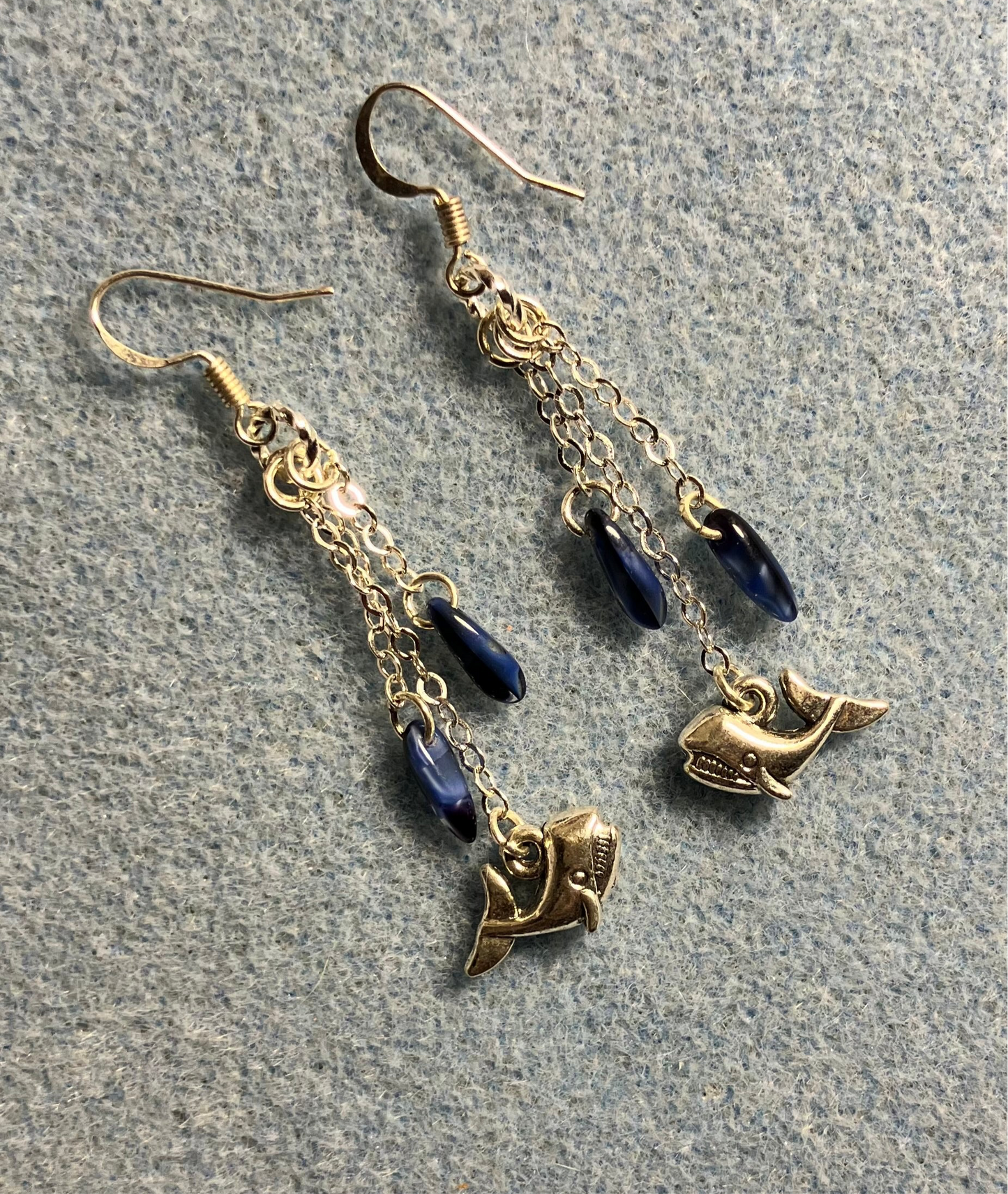Small silver whale charm earrings attached to silver chain and adorned with small dark blue Czech glass dagger beads