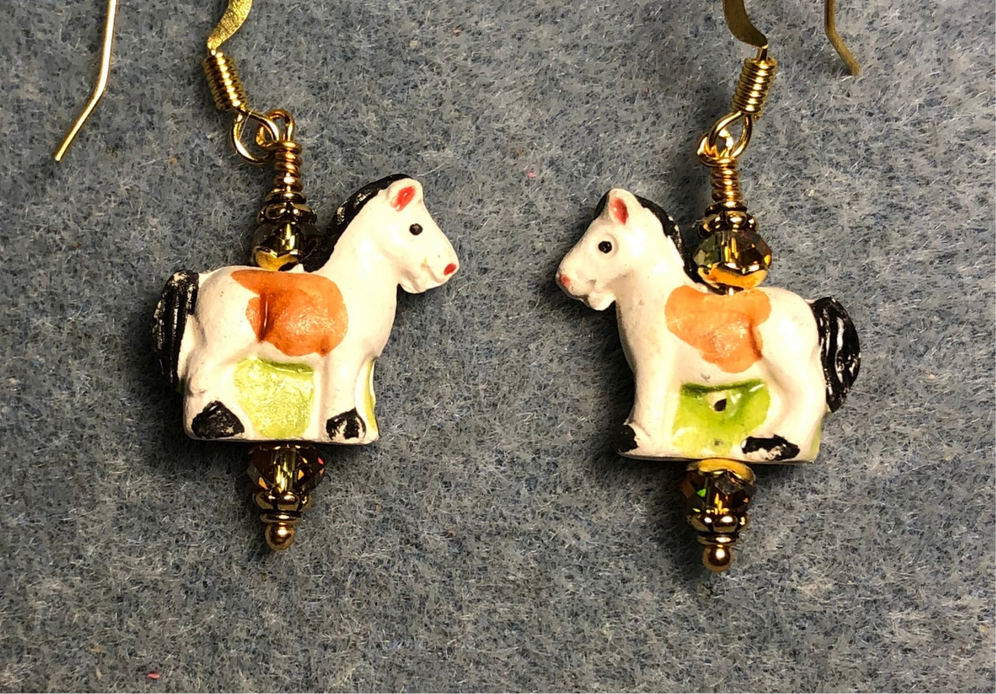 Small white, amber, and olive green ceramic horse bead earrings adorned with olive green Chinese crystal beads.