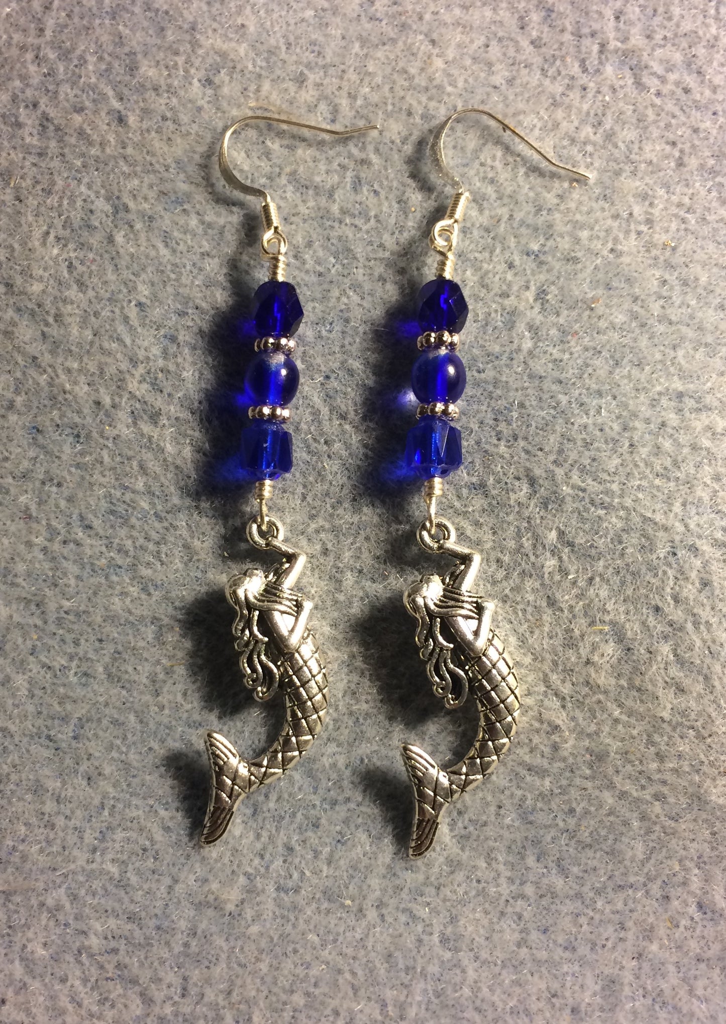 Long silver mermaid charm earrings adorned with dark blue Czech glass beads