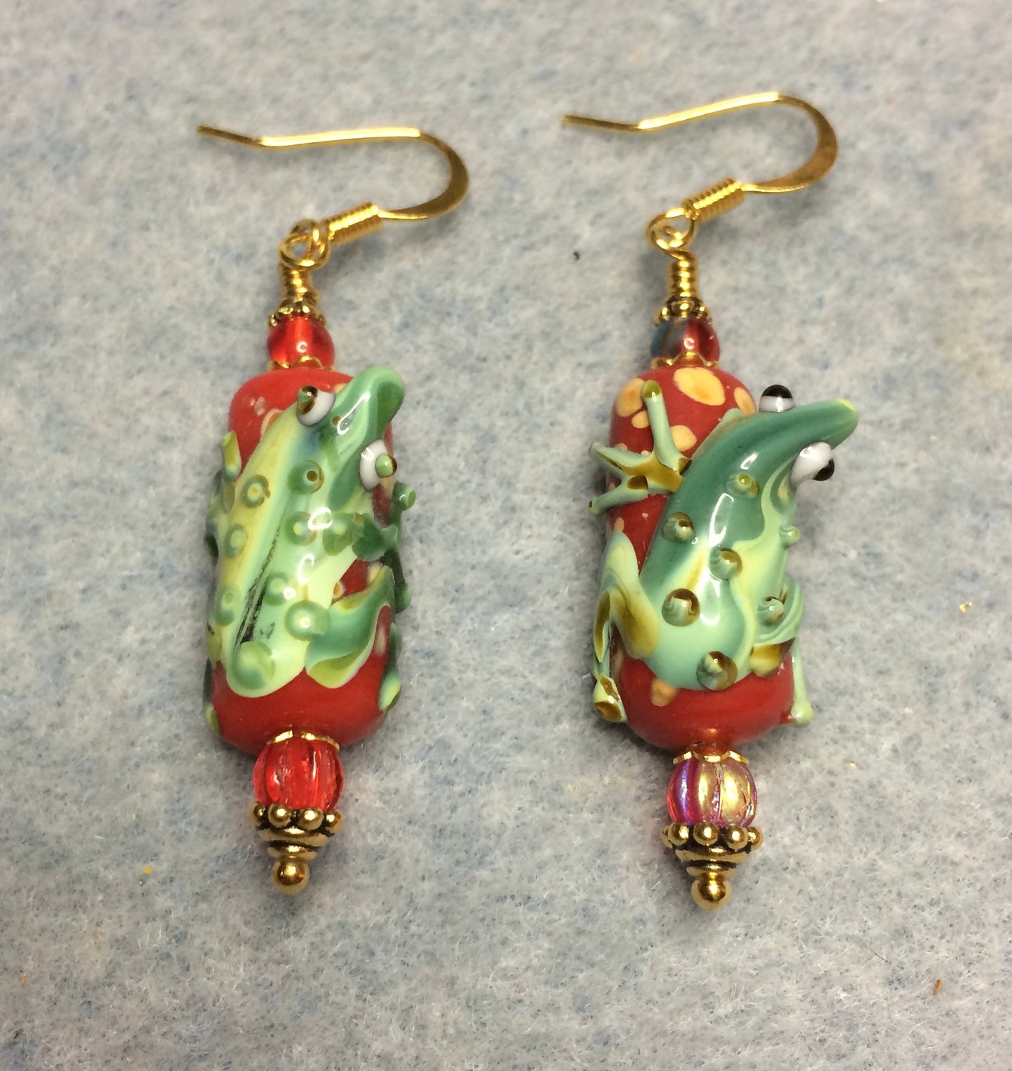 Red and green lamp work lizard bead earrings adorned with red Czech glass beads.