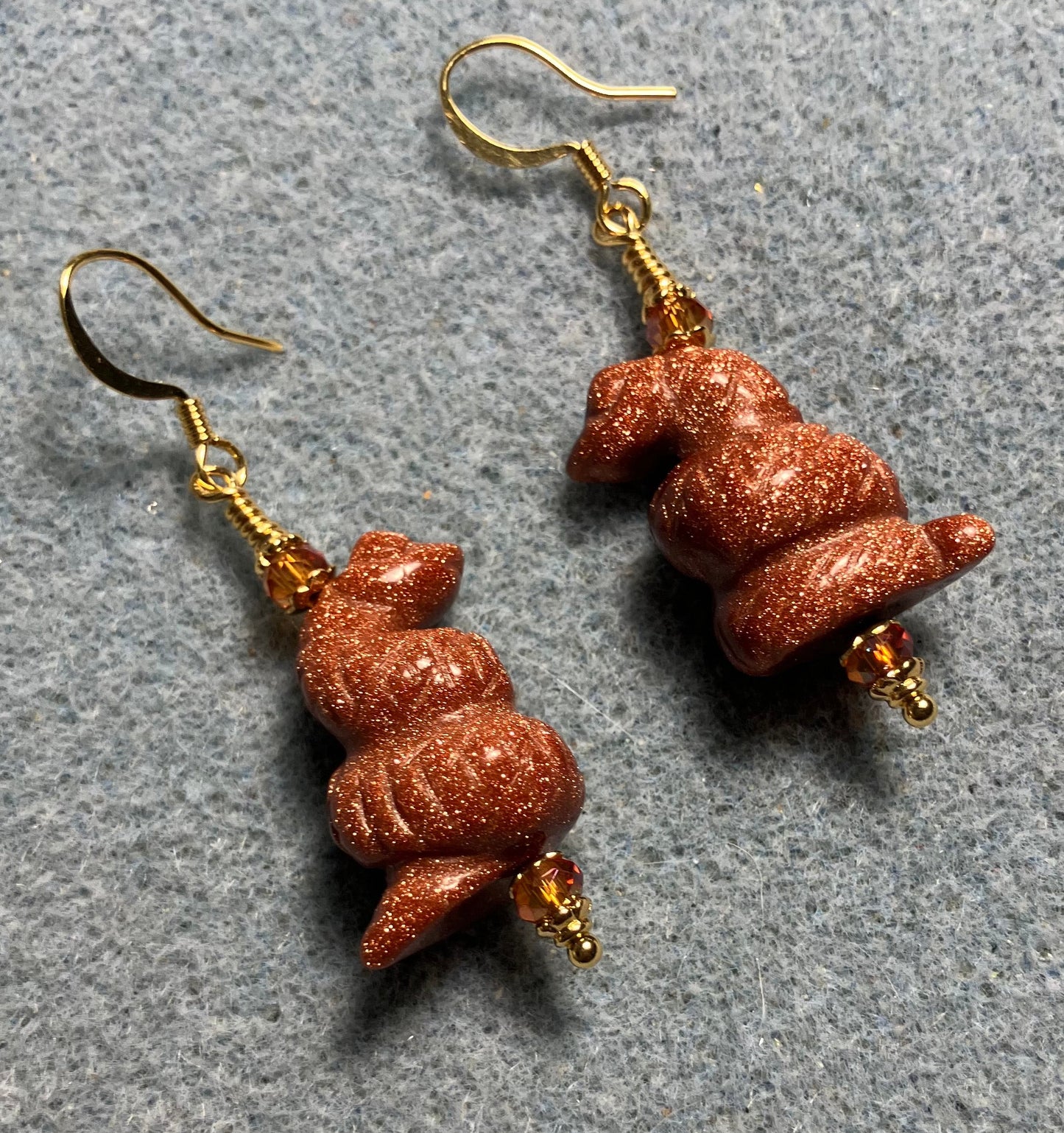 Goldstone gemstone coiled snake bead earrings adorned with orange Chinese crystal beads.
