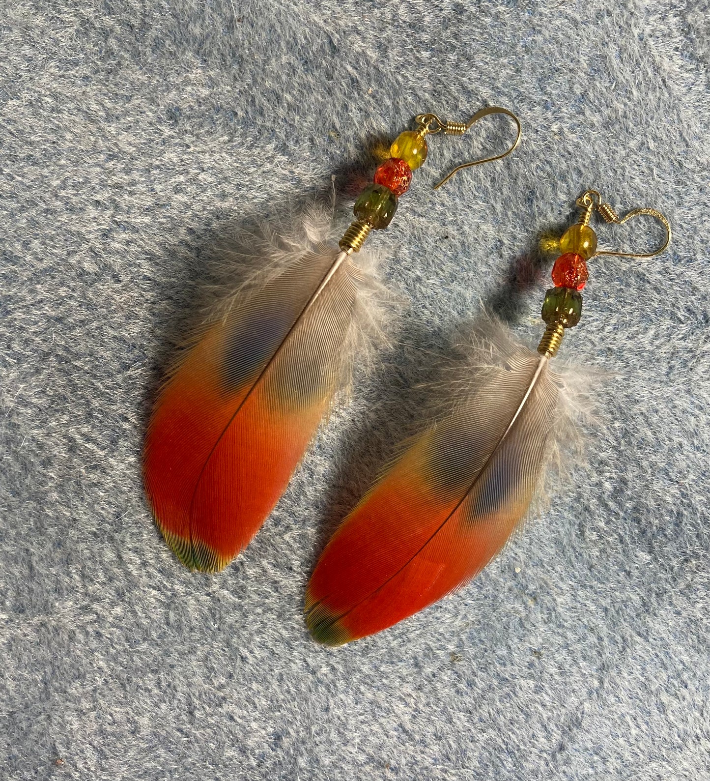 Red, yellow, and green scarlet macaw feather earrings adorned with red, yellow, and green Czech glass beads.
